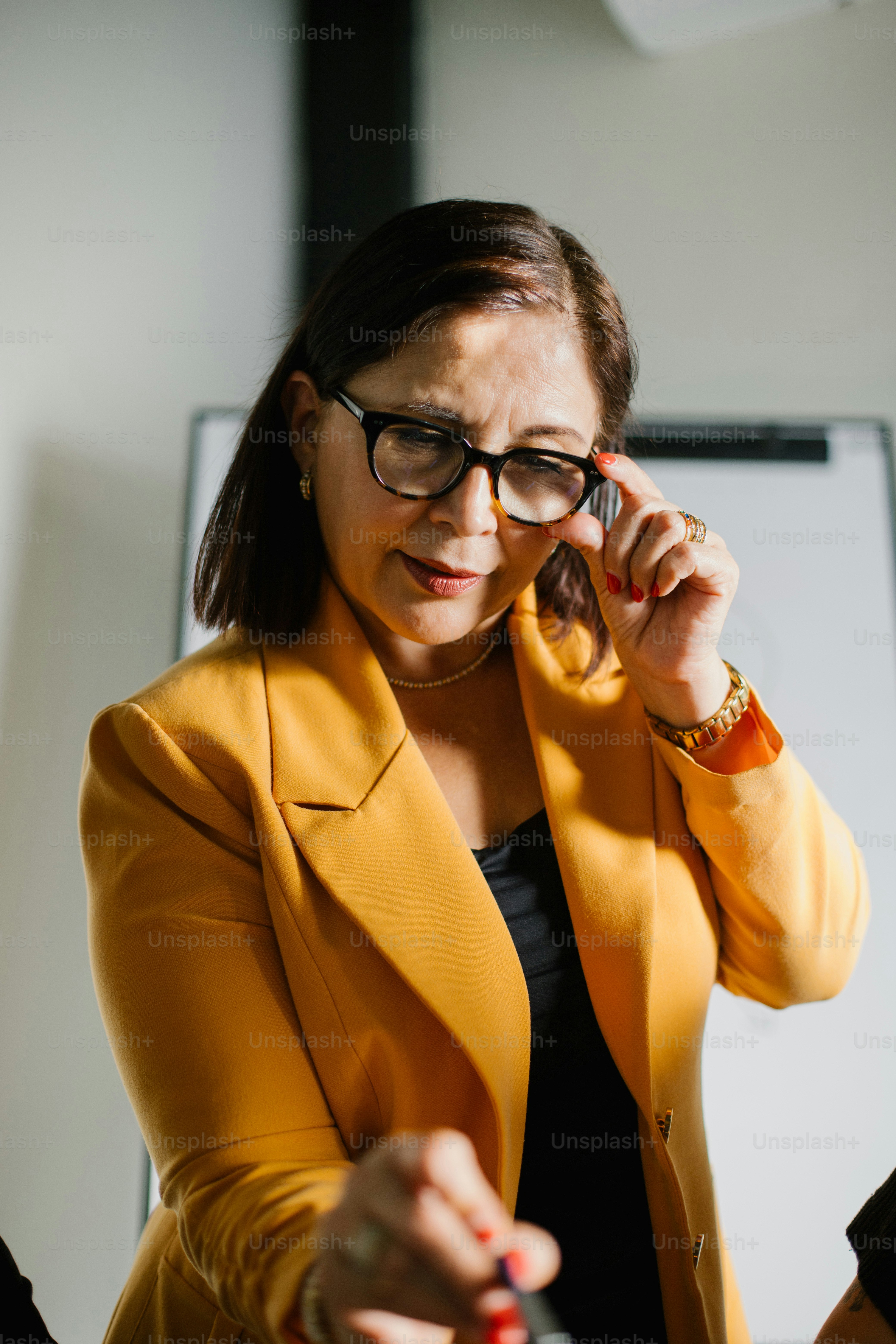 A businesswoman looks over her glasses in concentration.