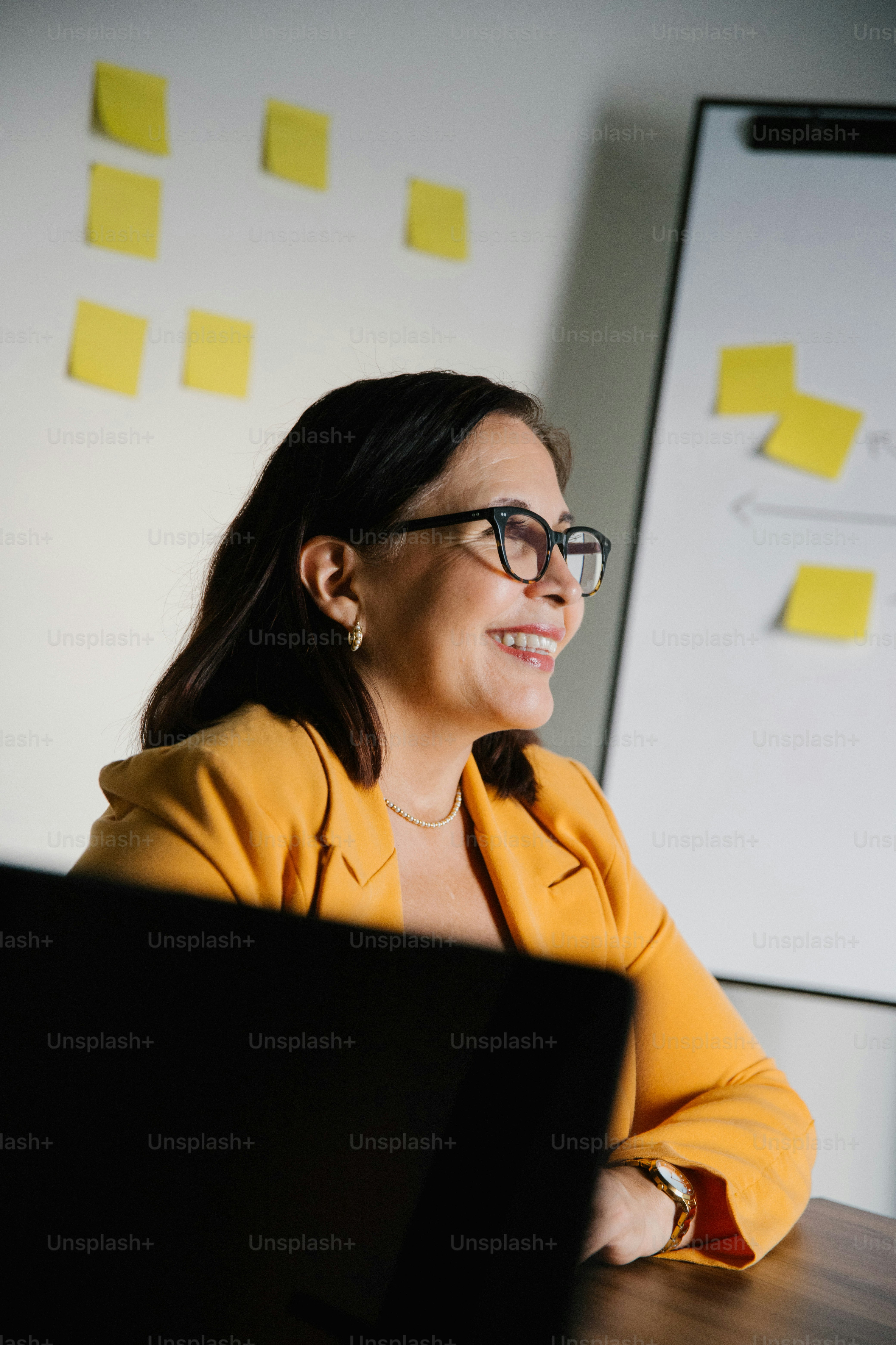 A smiling woman looks towards a whiteboard.