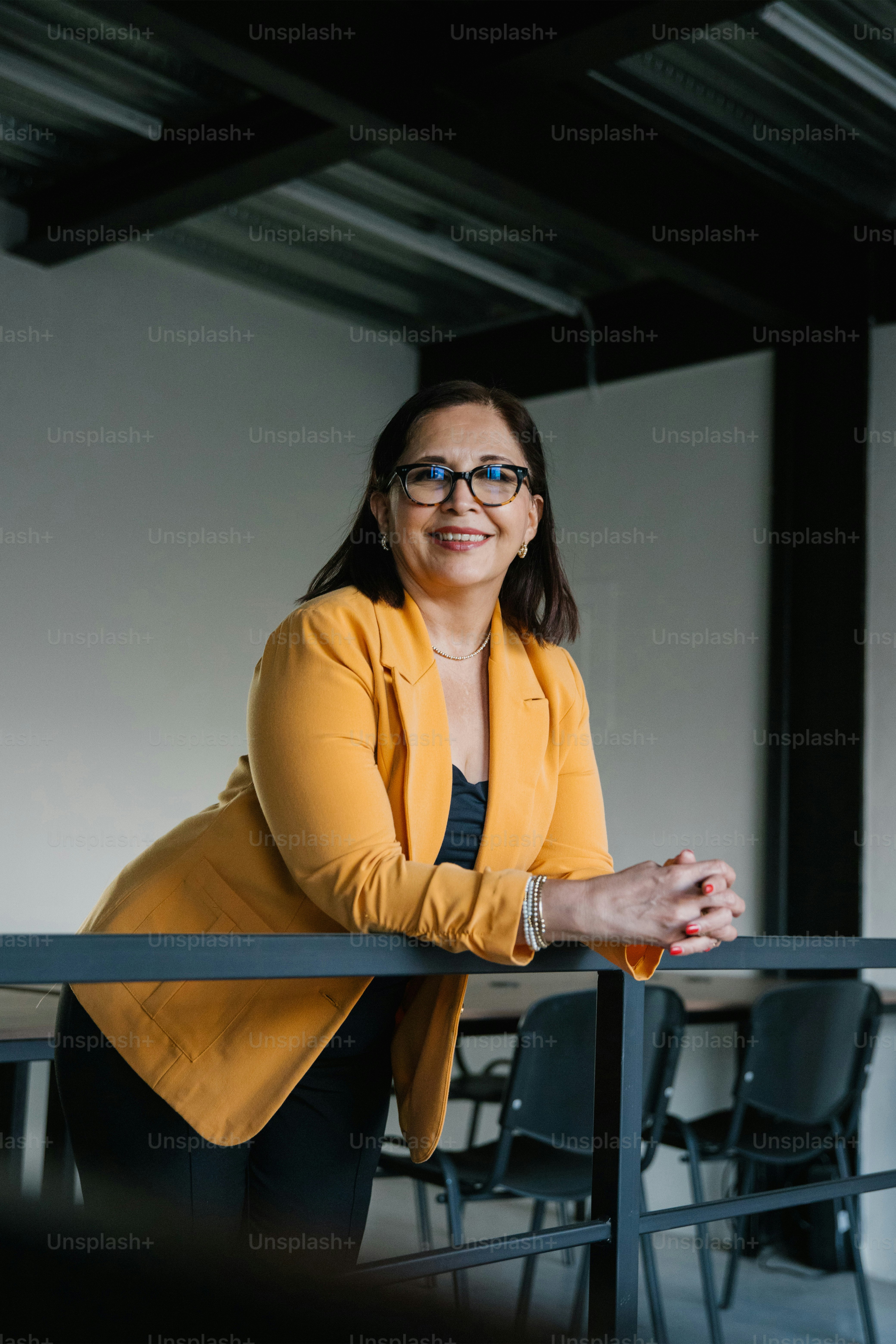A smiling businesswoman leans on a railing.
