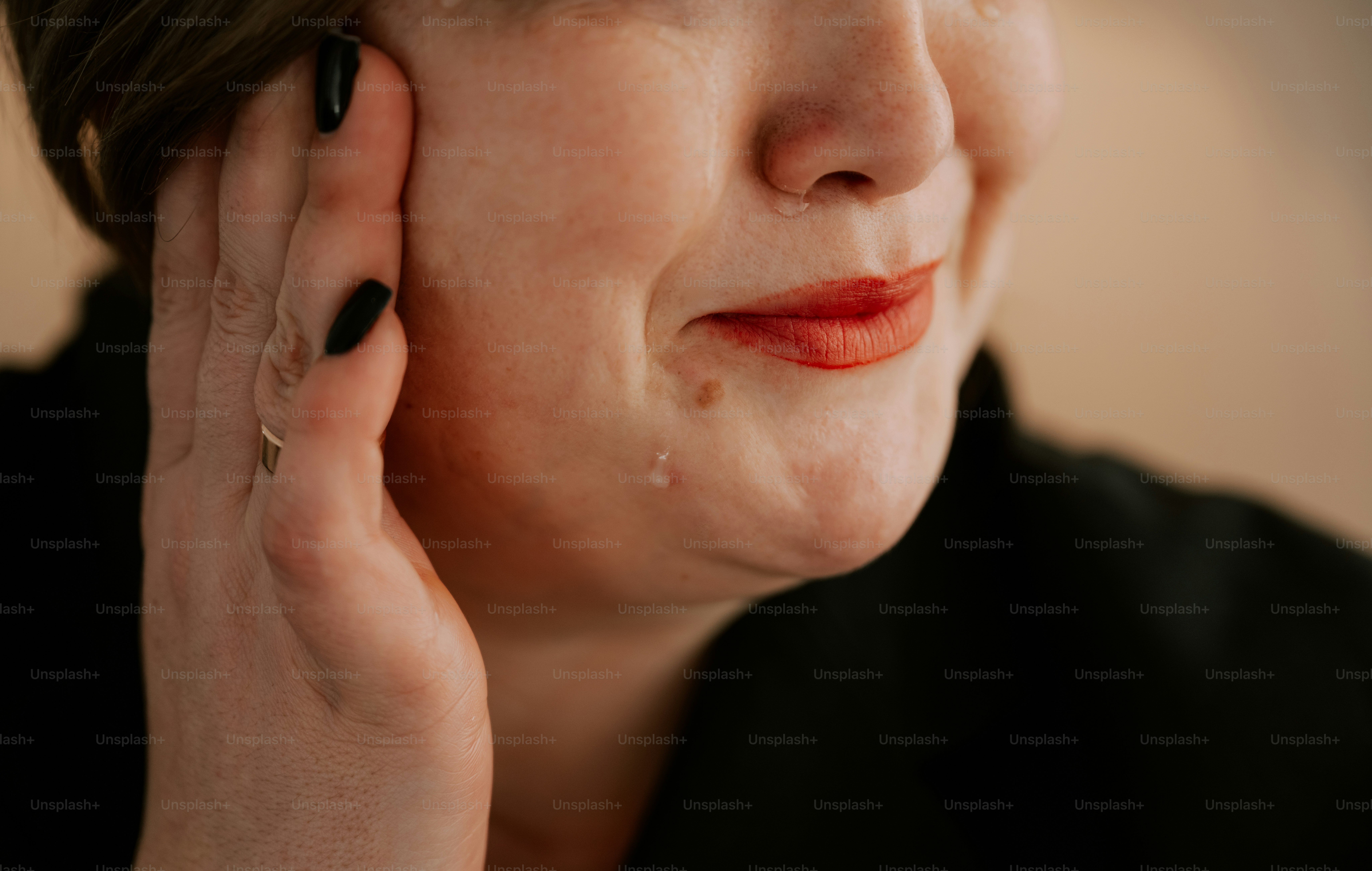 Woman clutches her face, looking thoughtful or in pain.