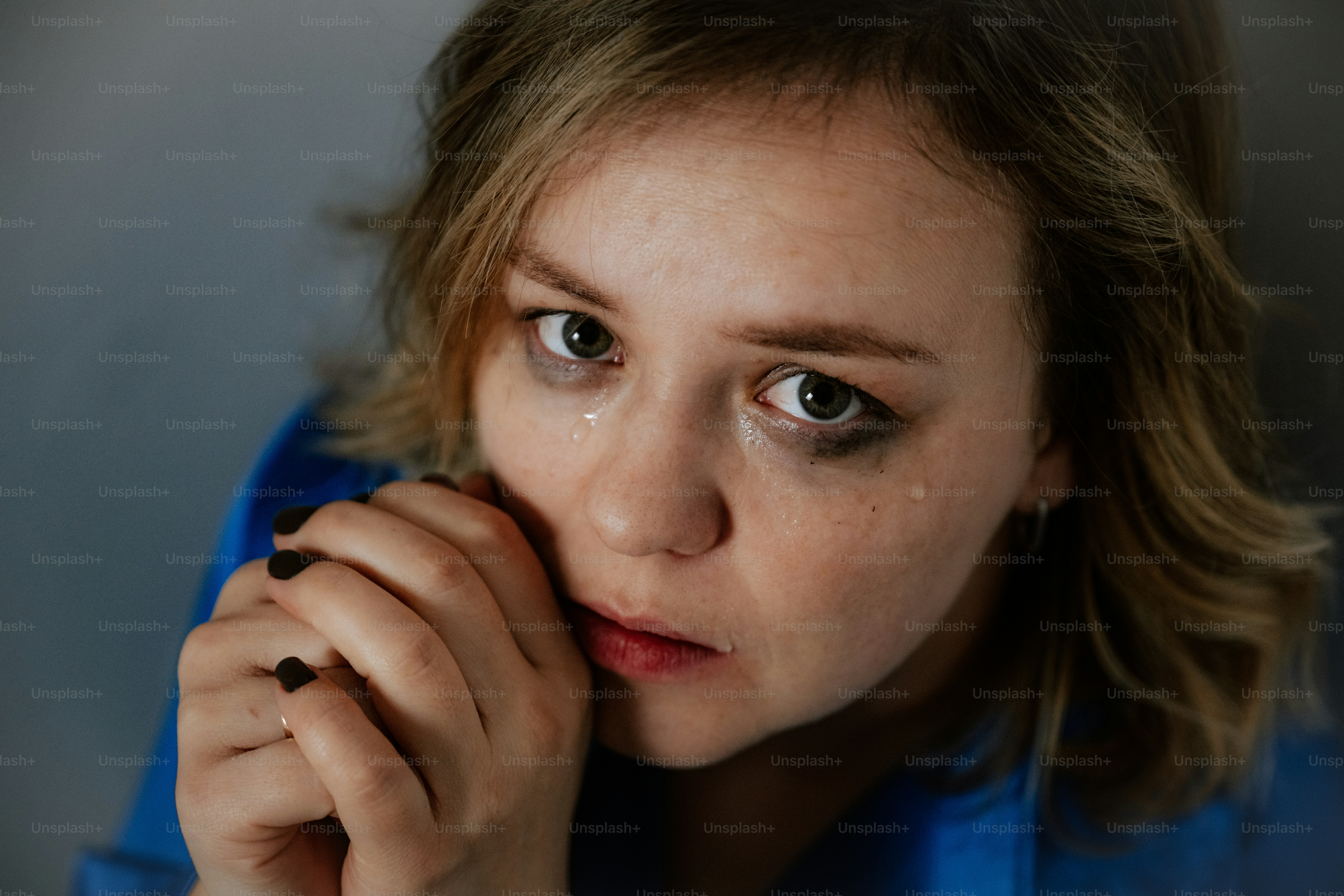 A crying woman looks directly at the camera.
