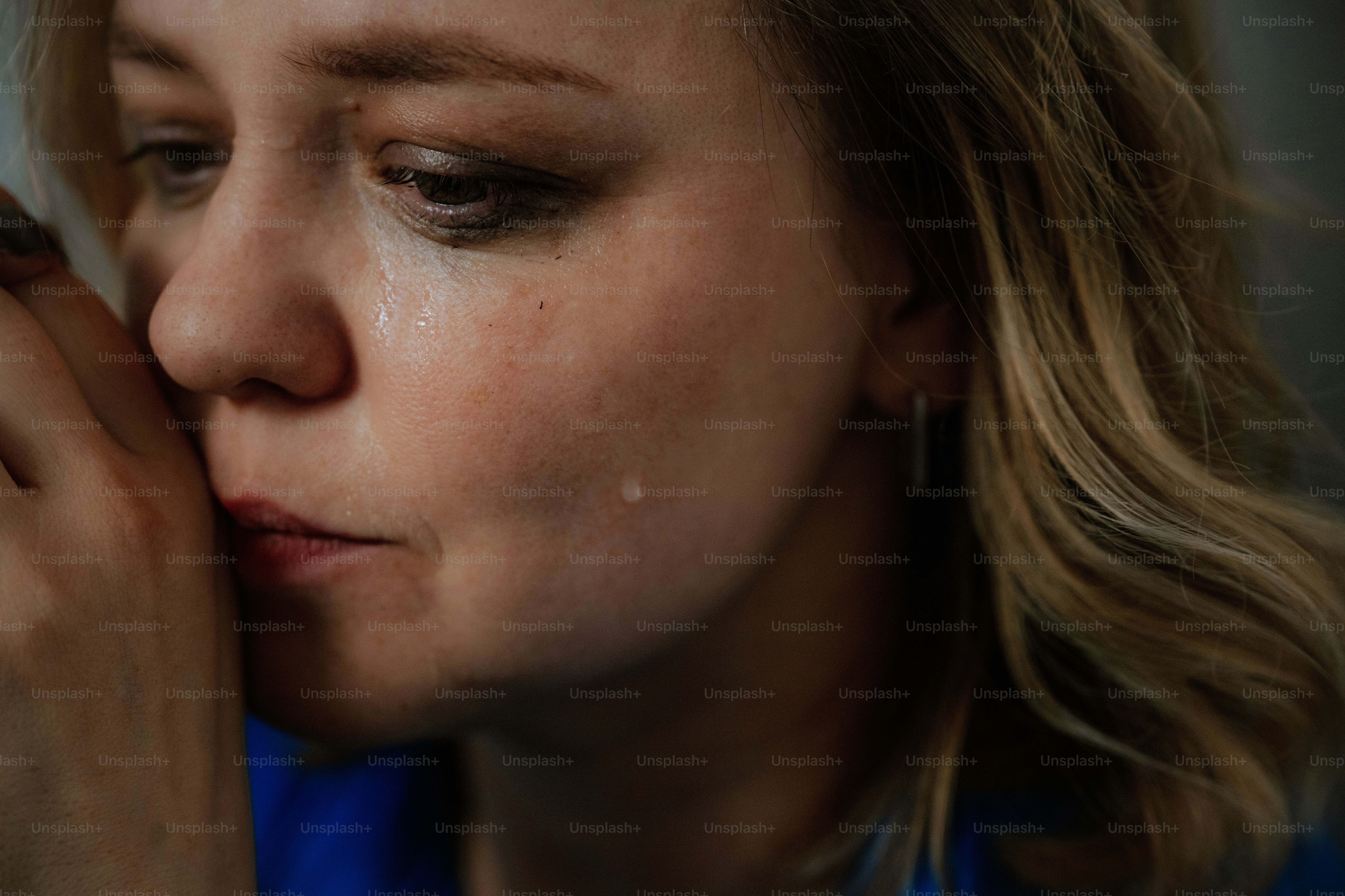 A woman sheds tears, looking sadly down.