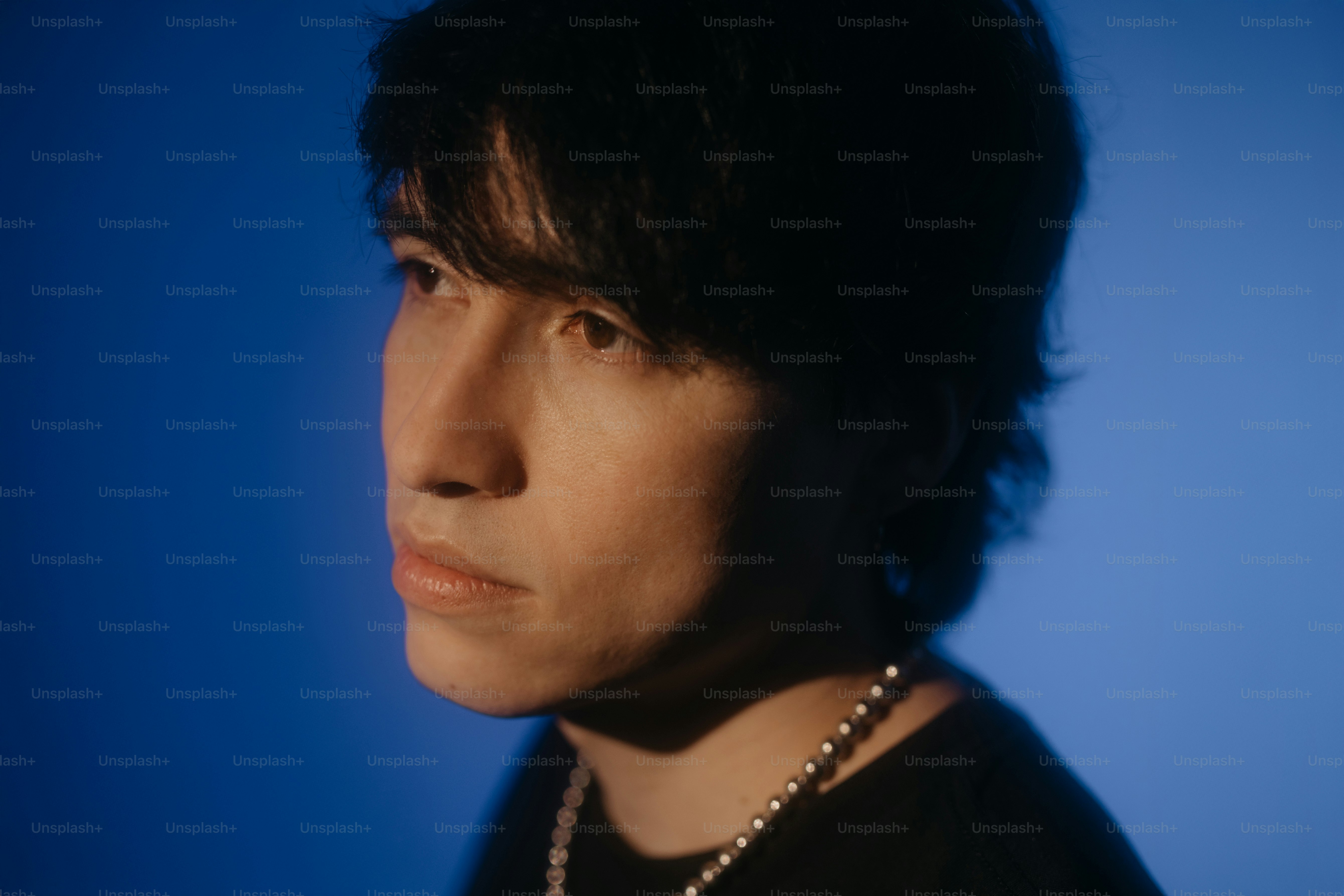 A person looks away with a dark blue background.