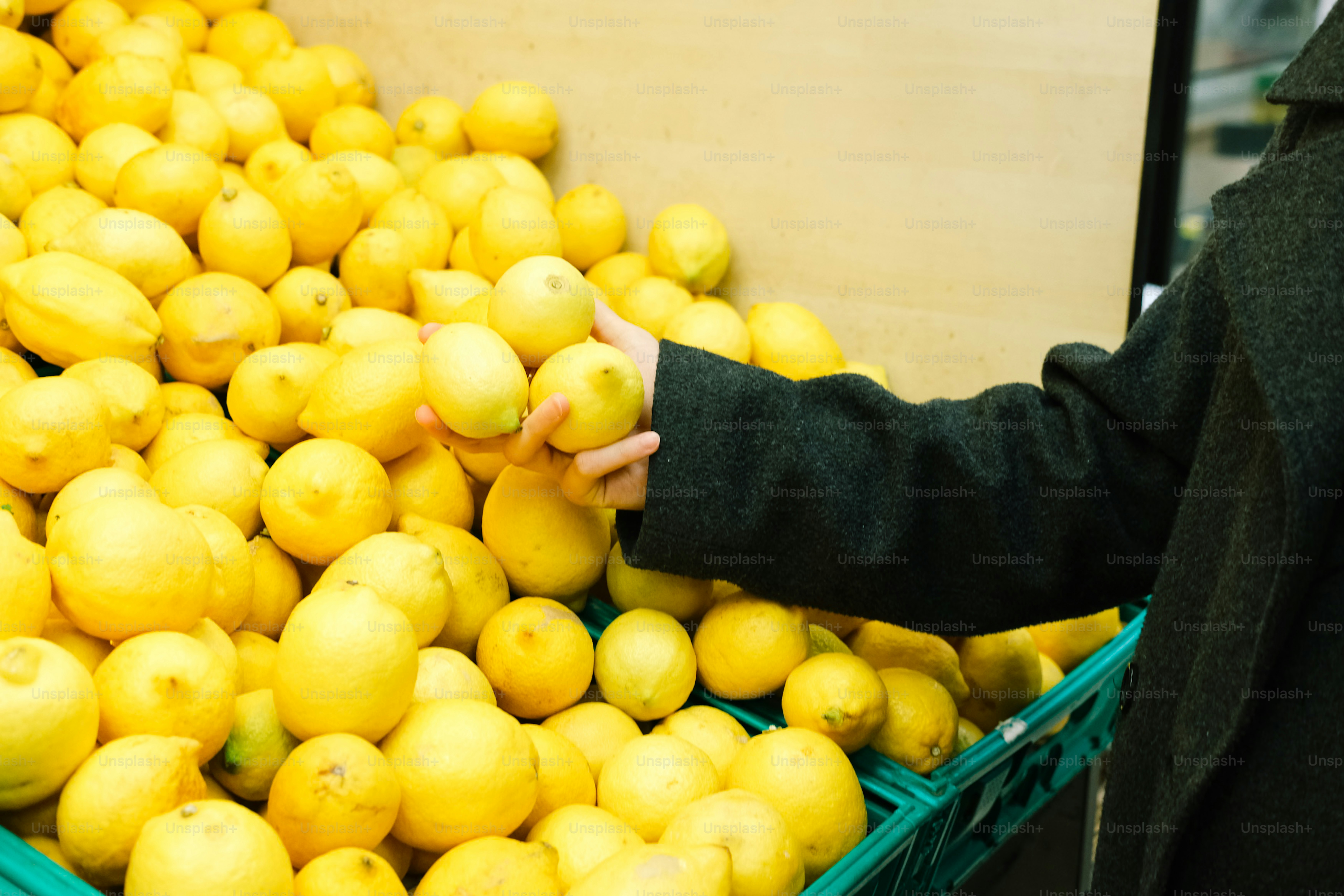 A hand reaches for a lemon in a grocery store. photo – Shopping Image ...