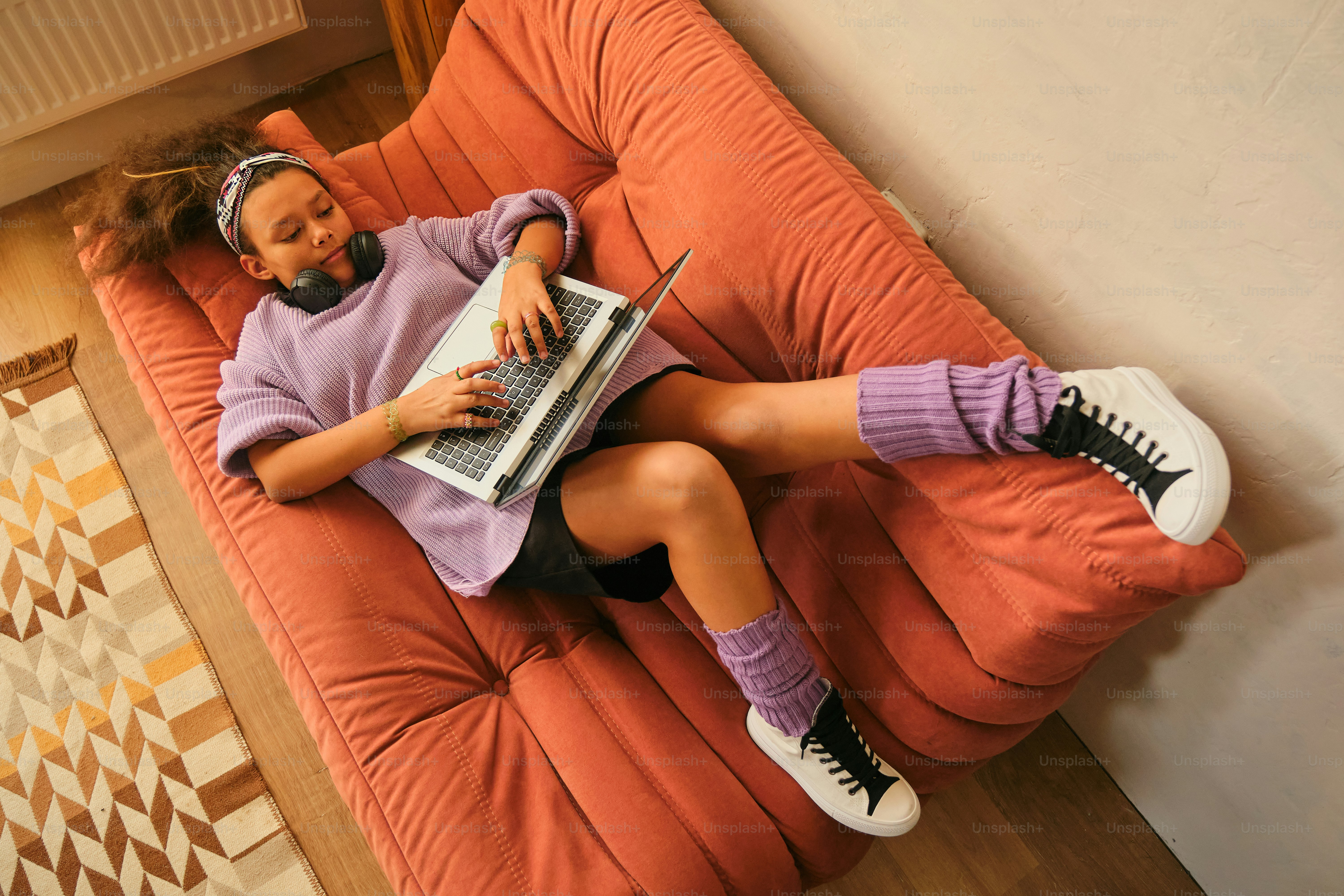 Girl relaxes with a laptop on a couch.