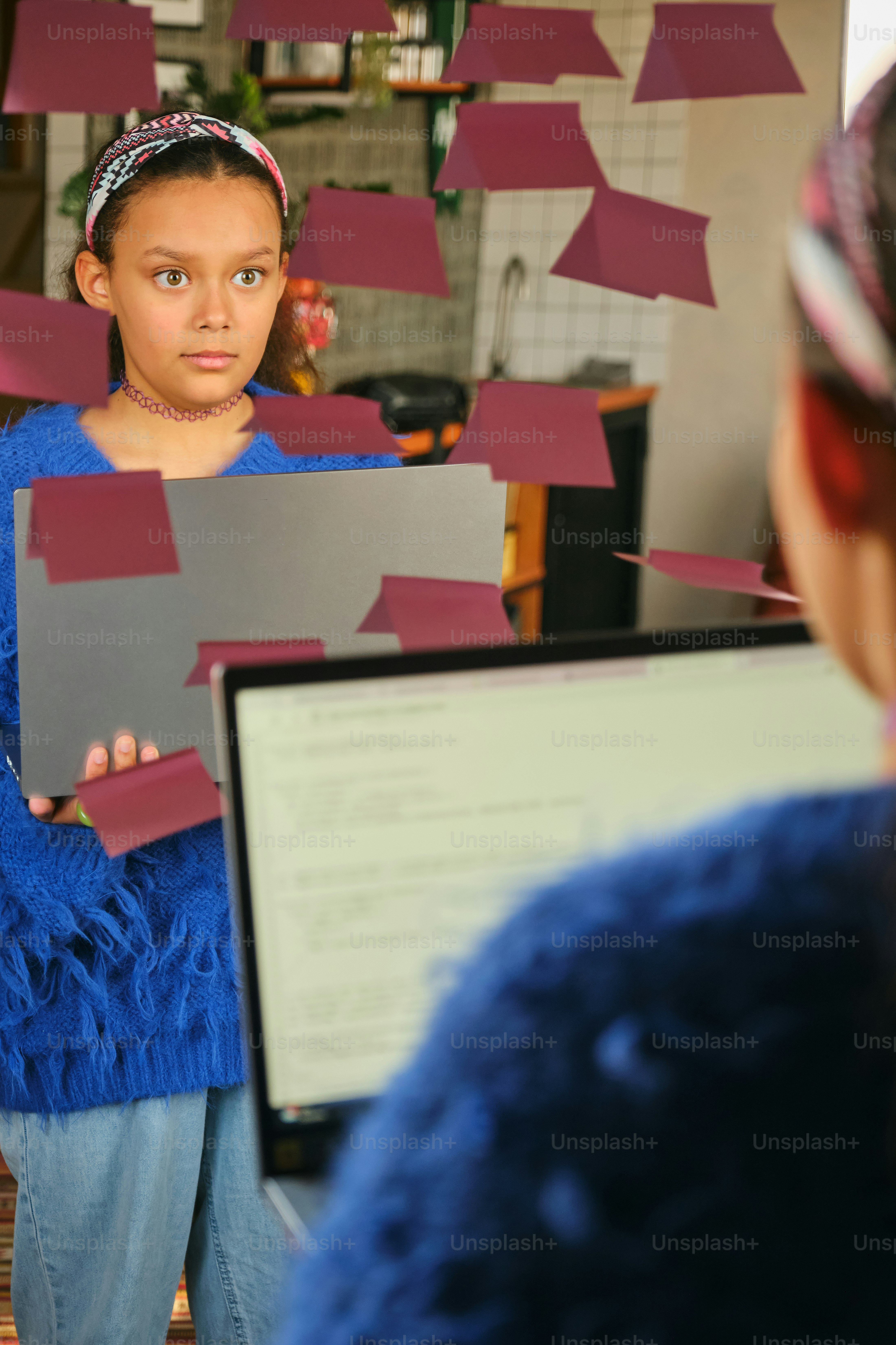 Girl stares at her reflection, laptop in hand.