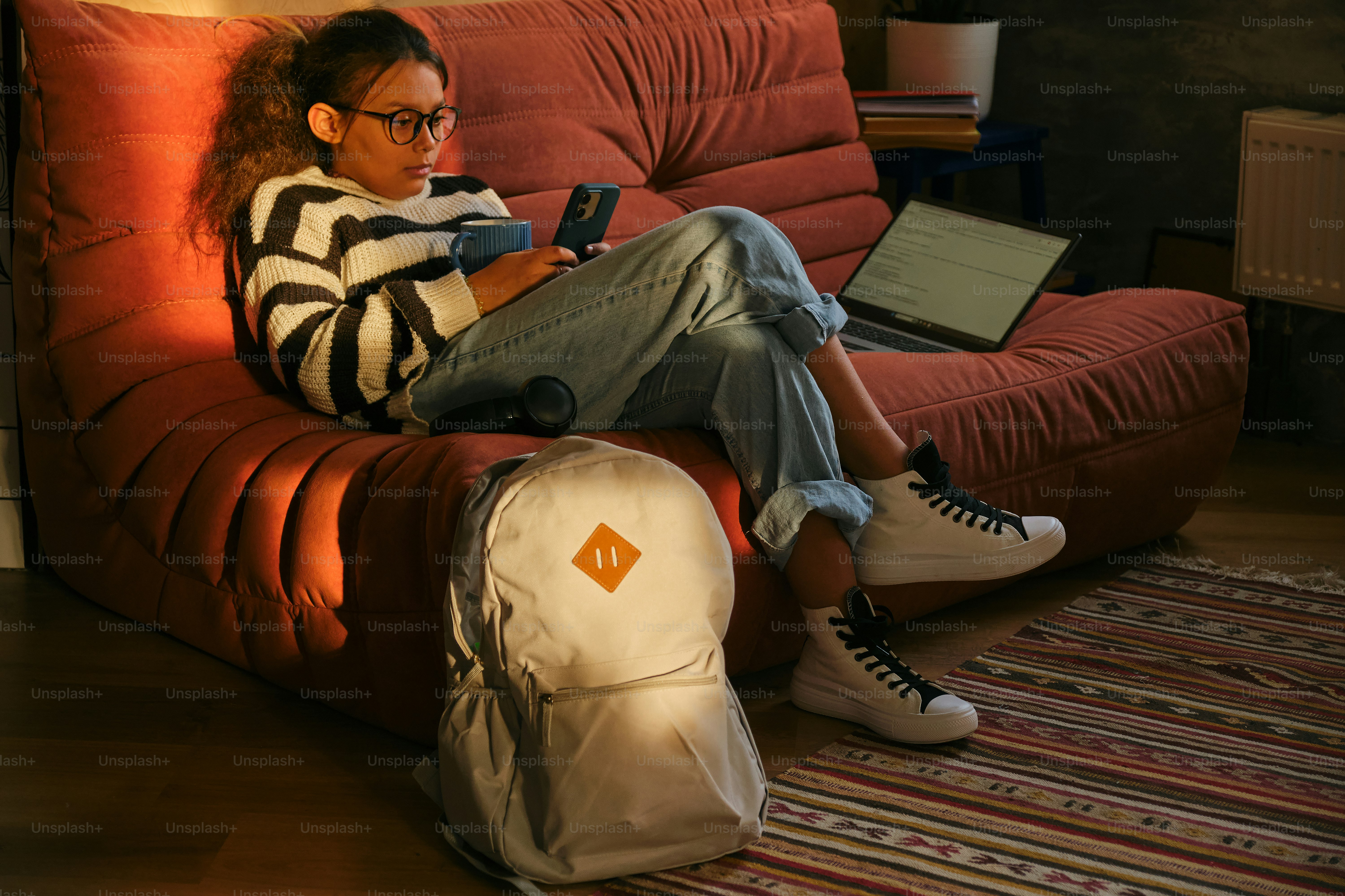 A young woman relaxes on a couch, using her phone.