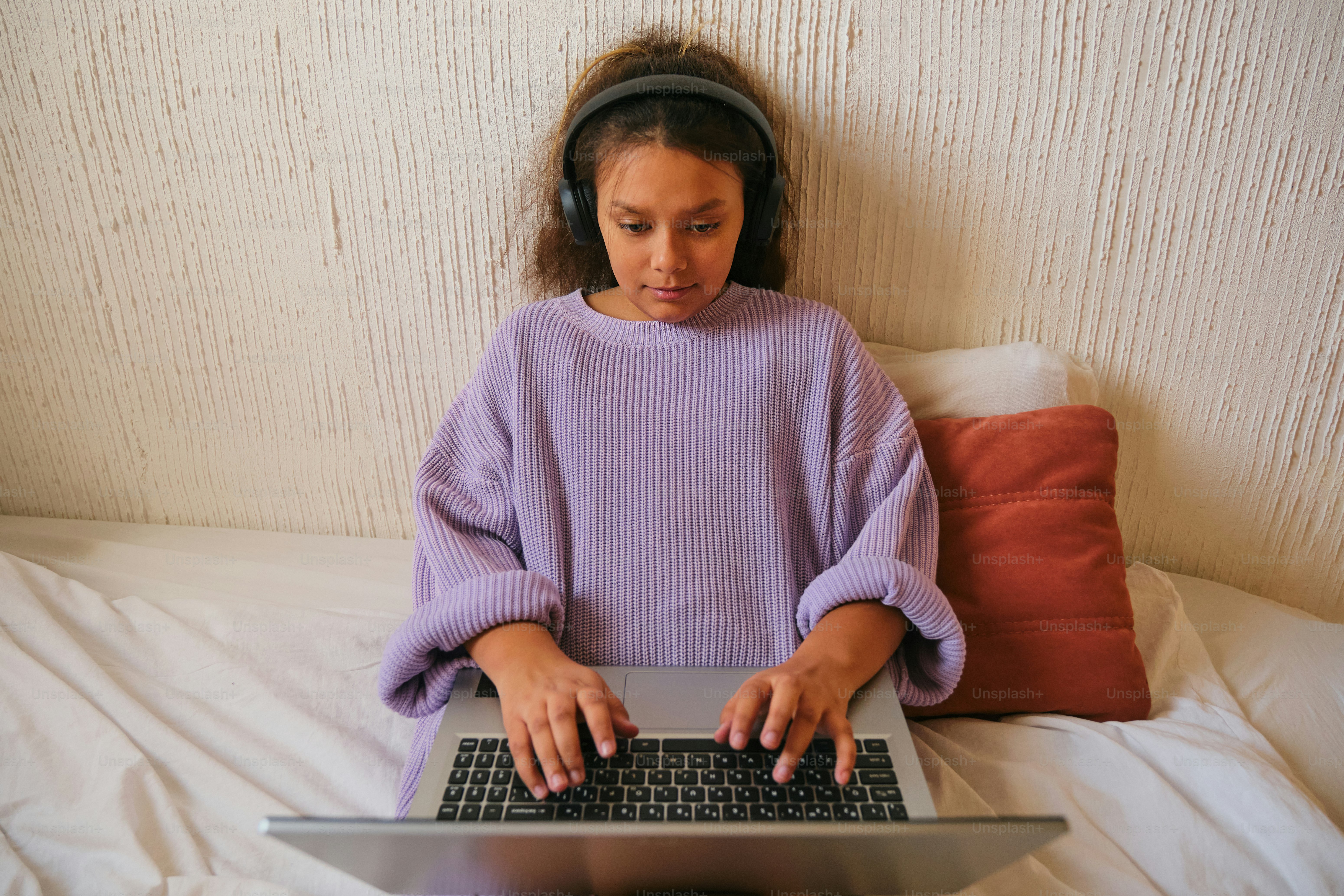 女の子はヘッドフォンを着けたままラップトップを使用します。