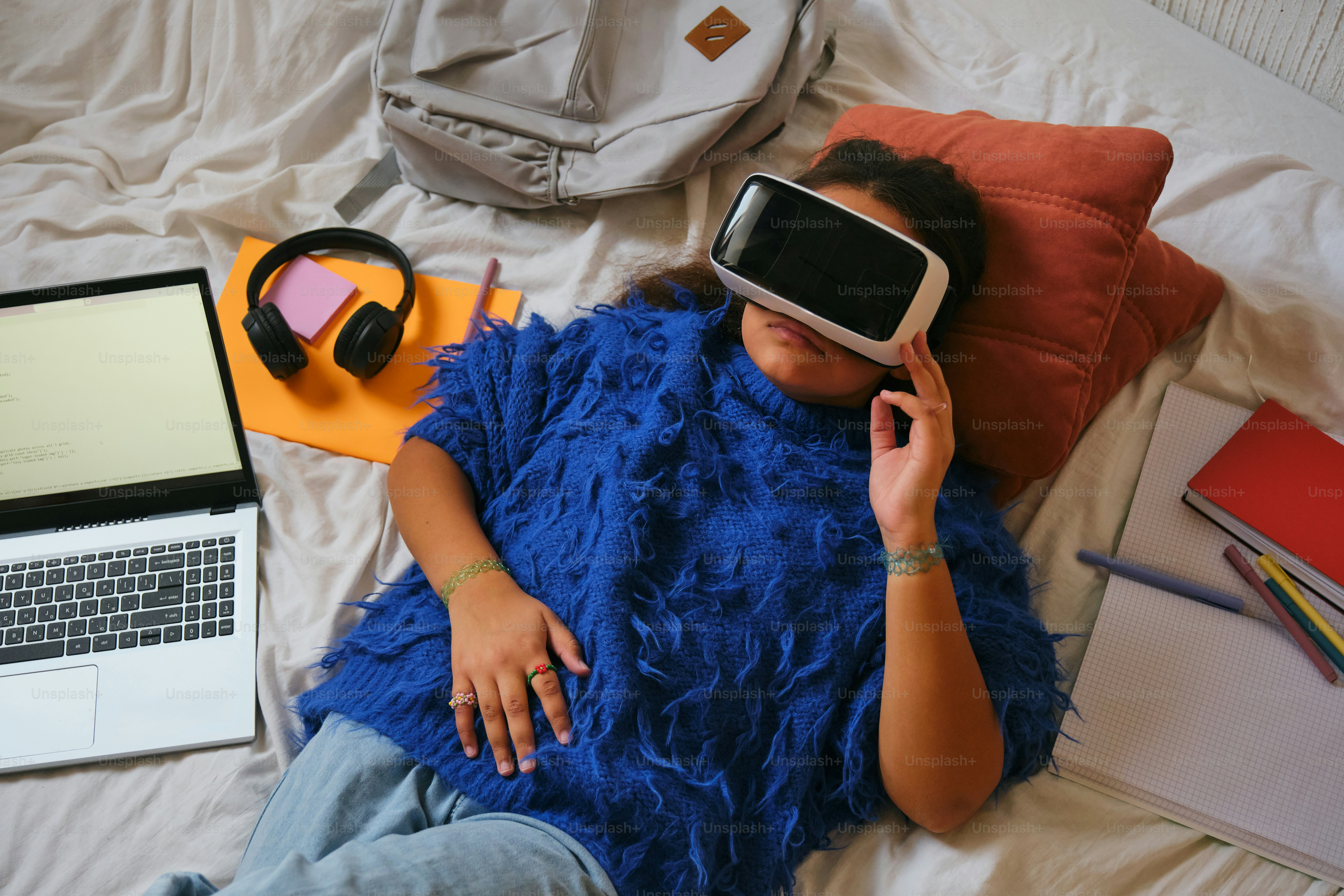 Woman wearing vr headset lies on a bed.