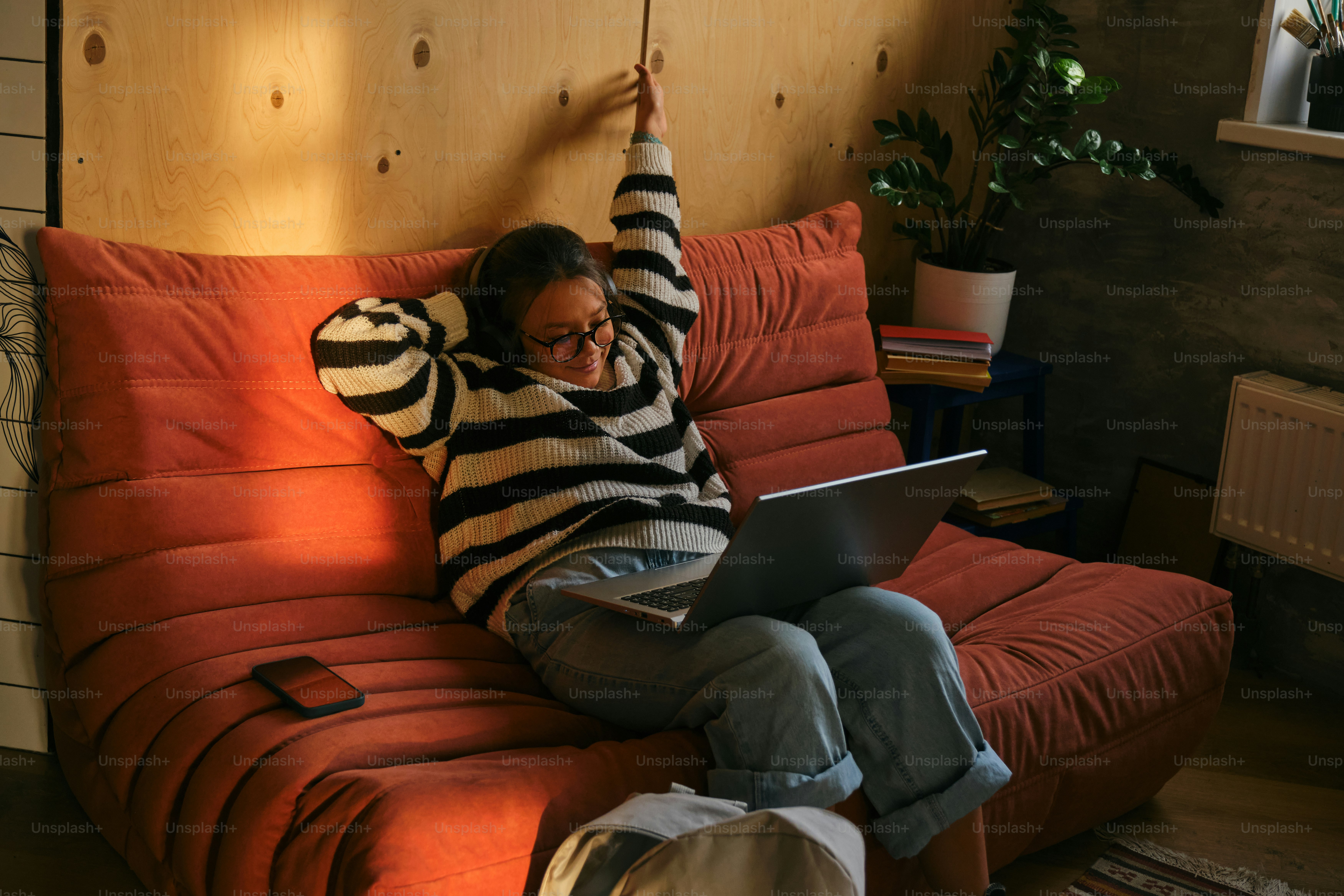 女性はラップトップを持ってソファでリラックスしています。