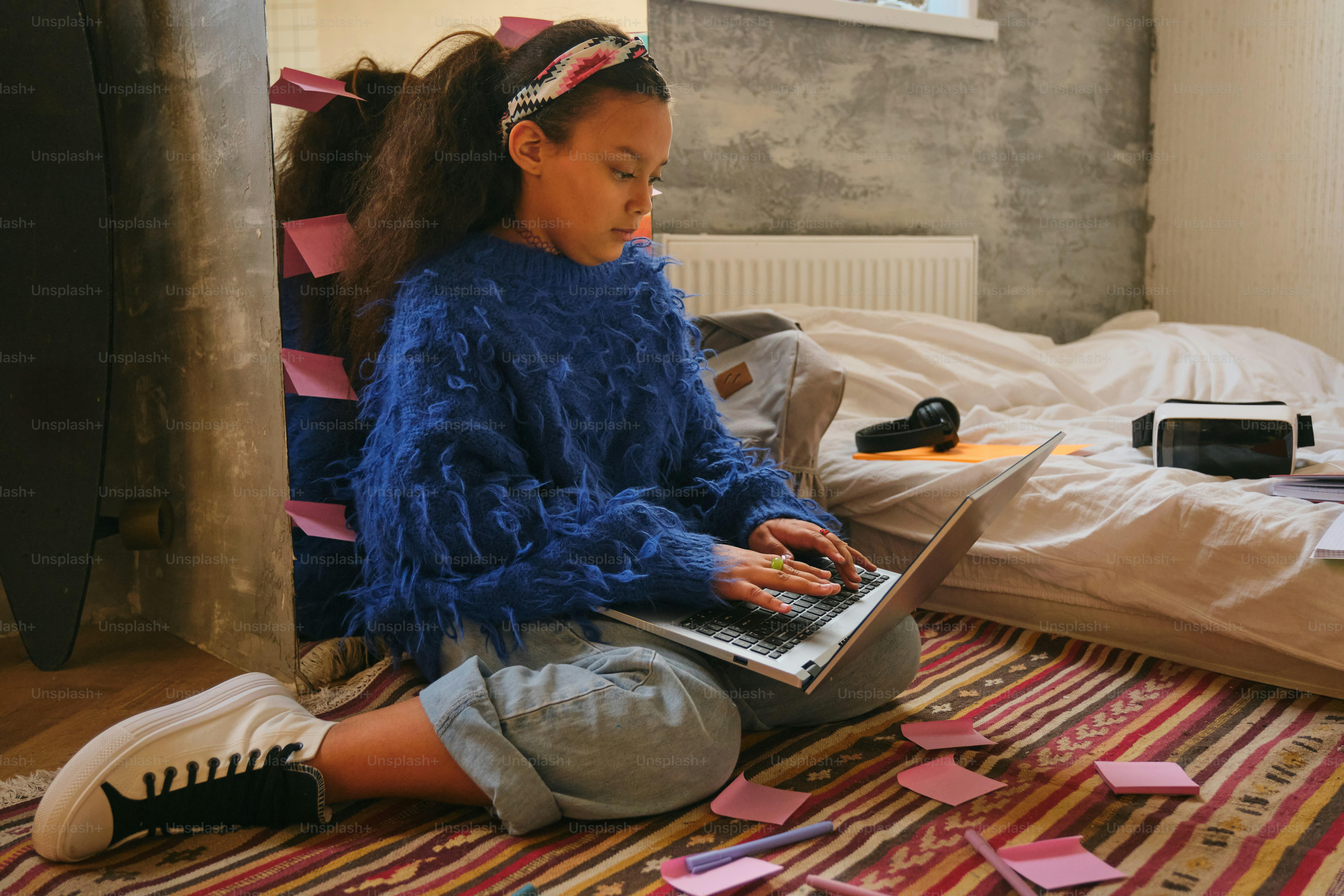 Girl uses laptop in a cozy room setting.