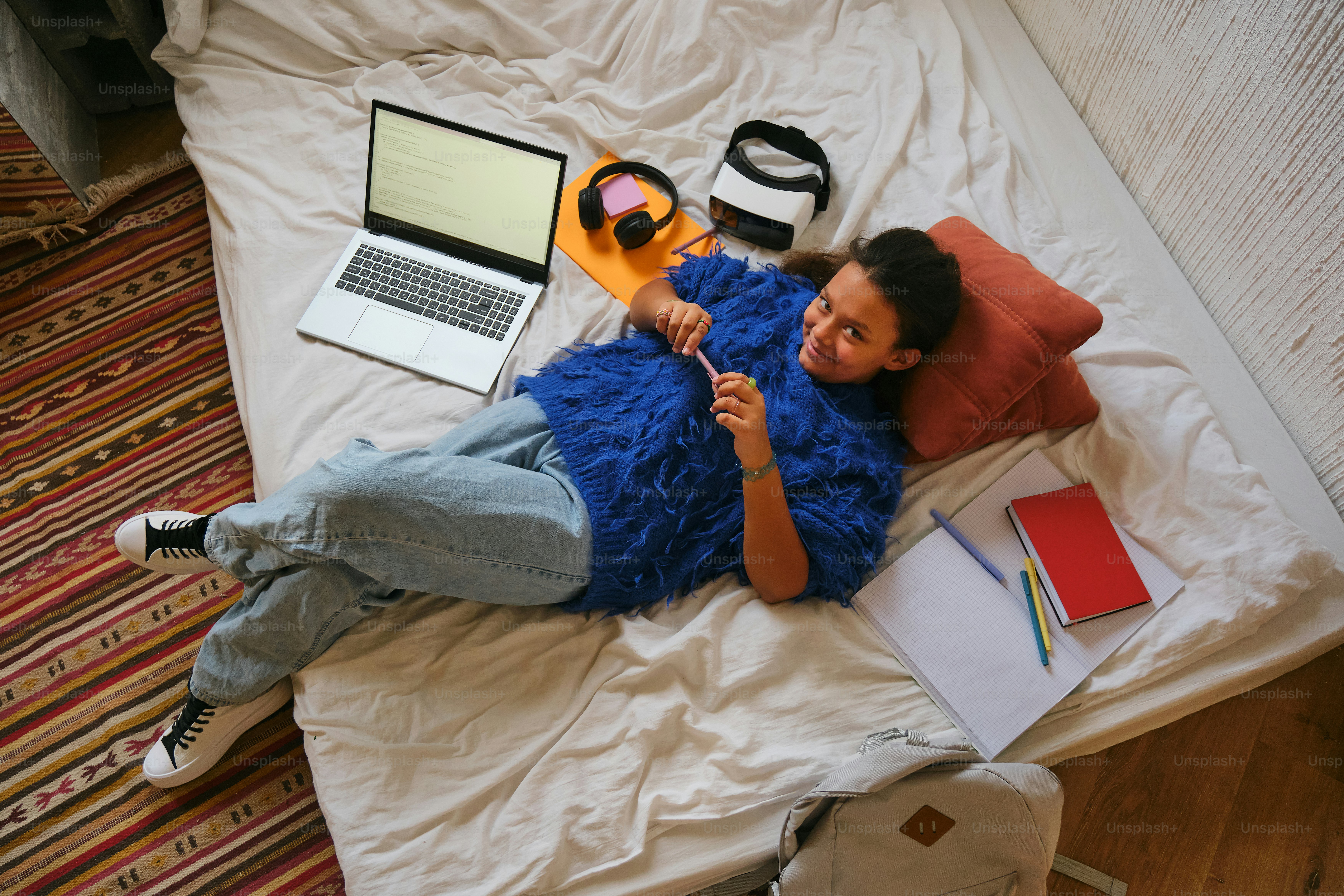 Woman lies on bed studying with a laptop.