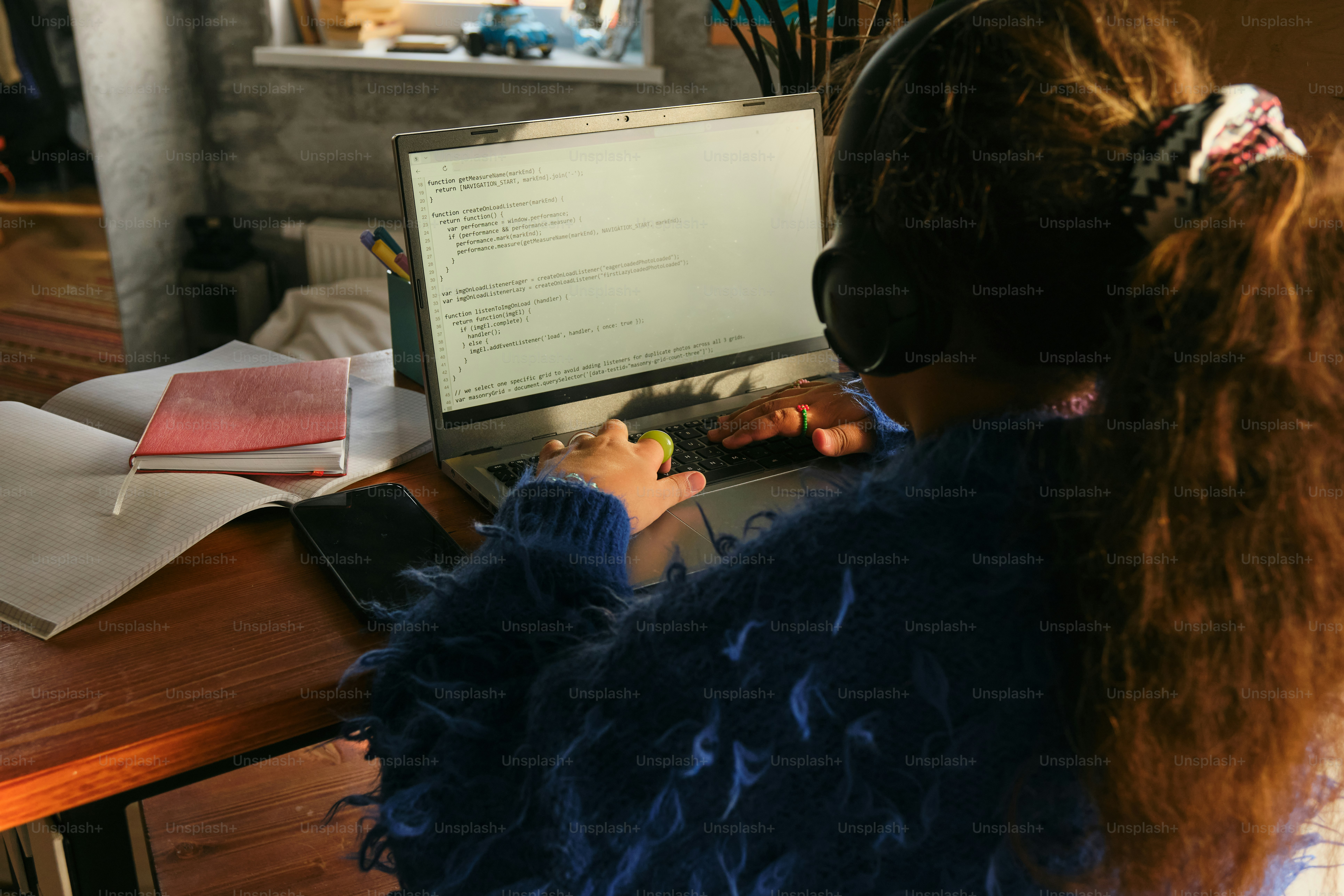 A girl studies at a laptop with headphones.