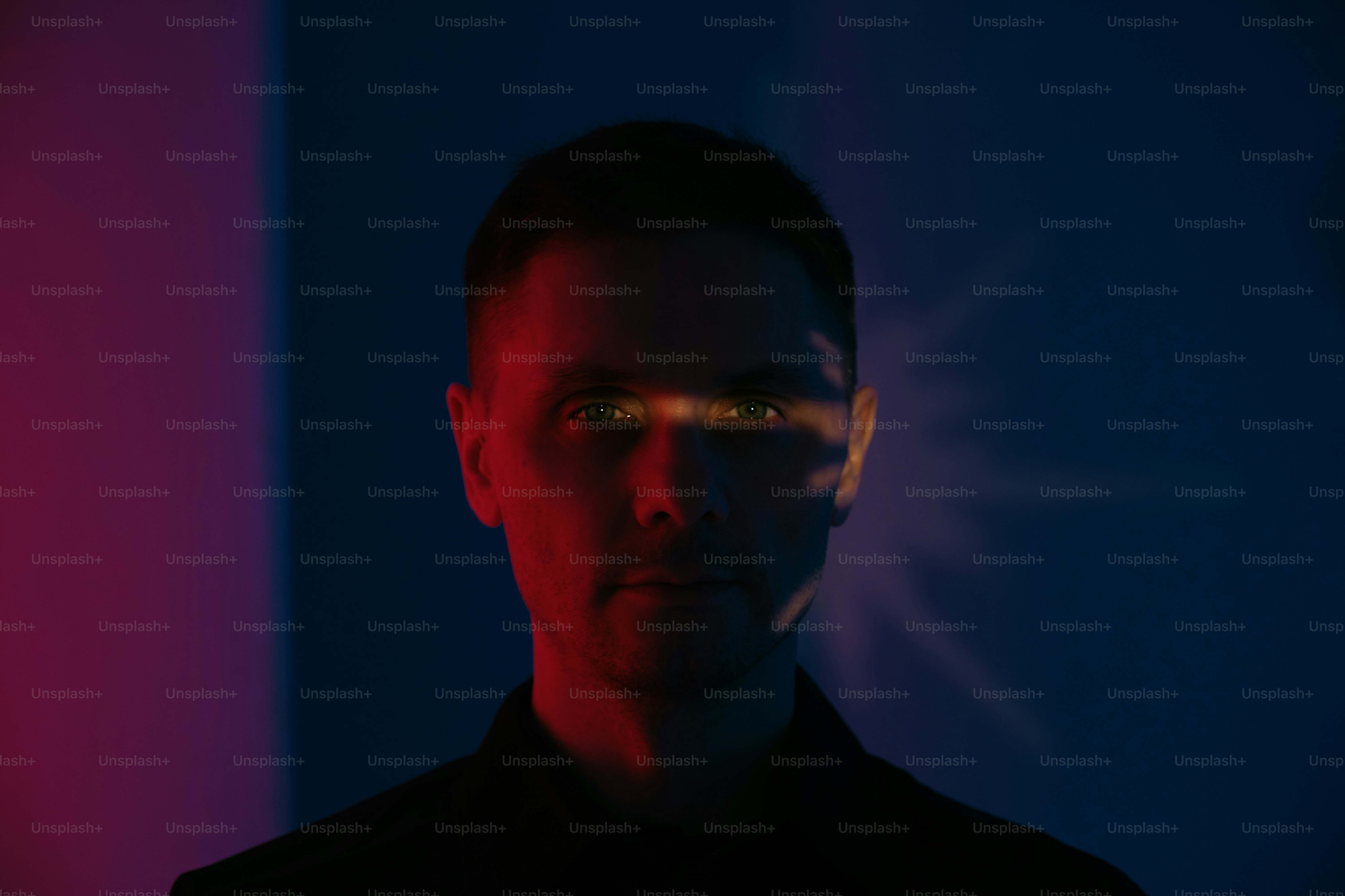 Man staring into the camera with colorful lighting.
