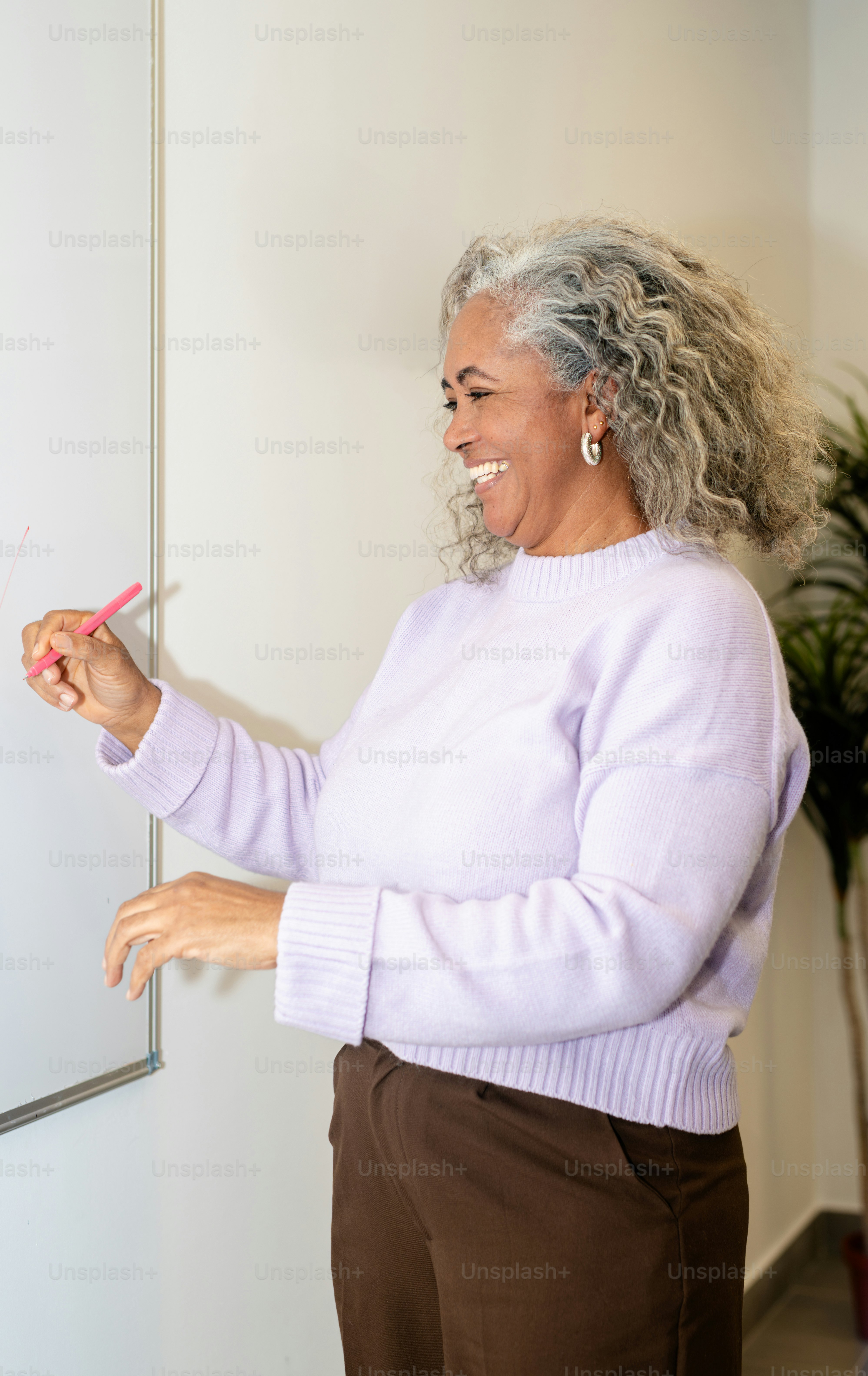 Frau schreibt lächelnd auf ein Whiteboard.