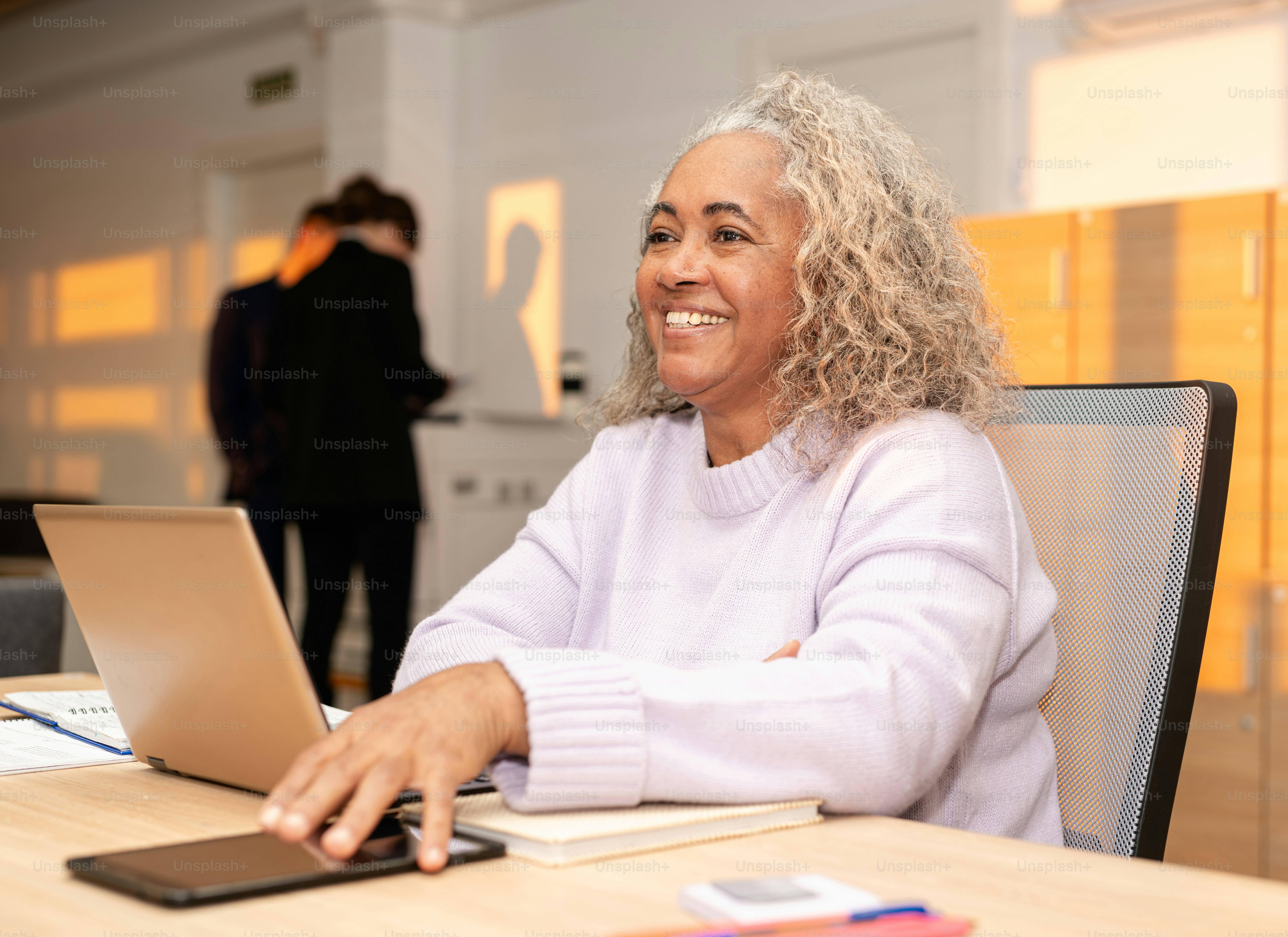 Lächelnde Frau benutzt ihren Laptop an einem Schreibtisch.