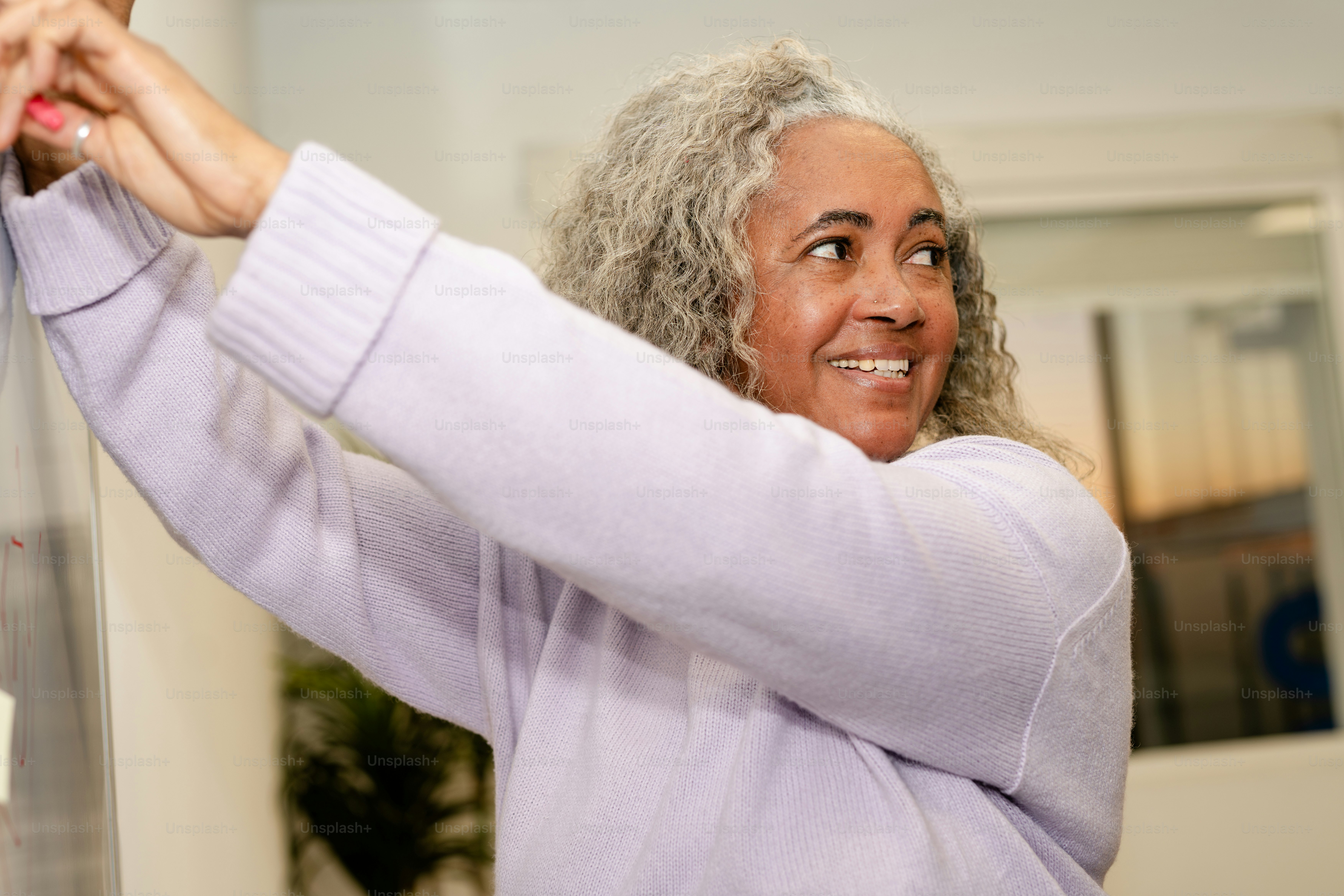 Frau lächelt, während sie ein Papier hochhält.