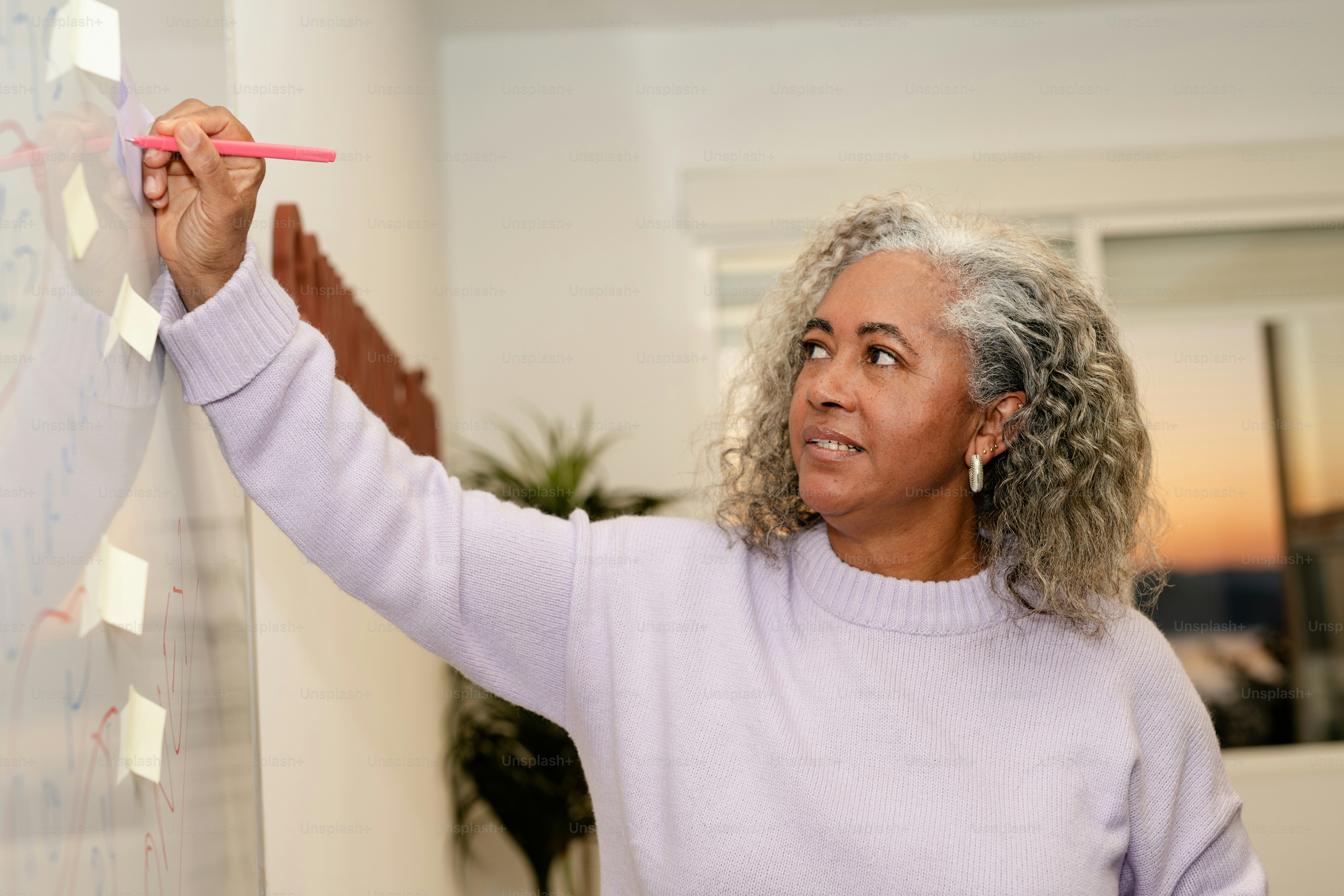 Woman writes on whiteboard with sticky notes.