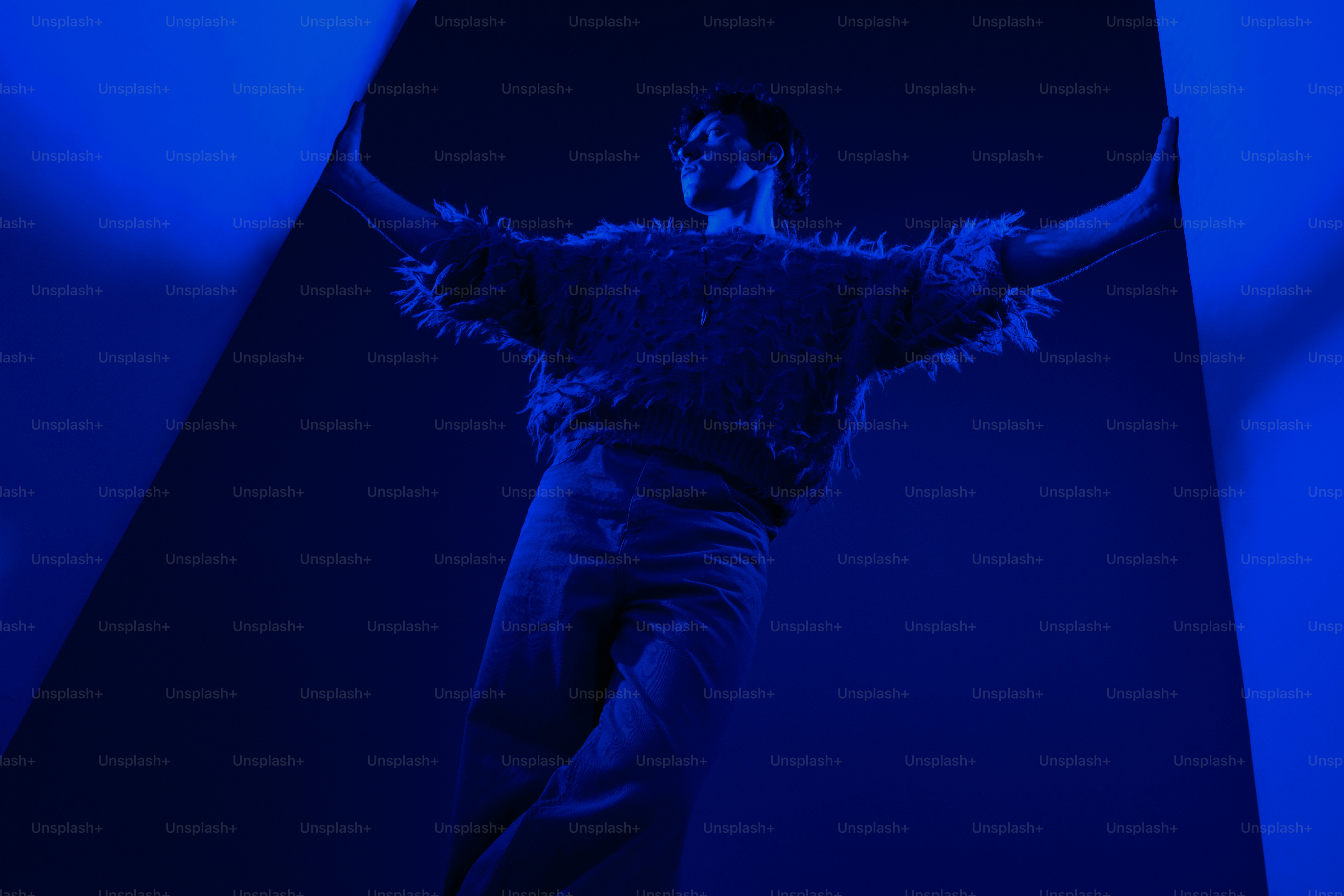 Eine Person mit erhobenen Armen in blauem Licht.