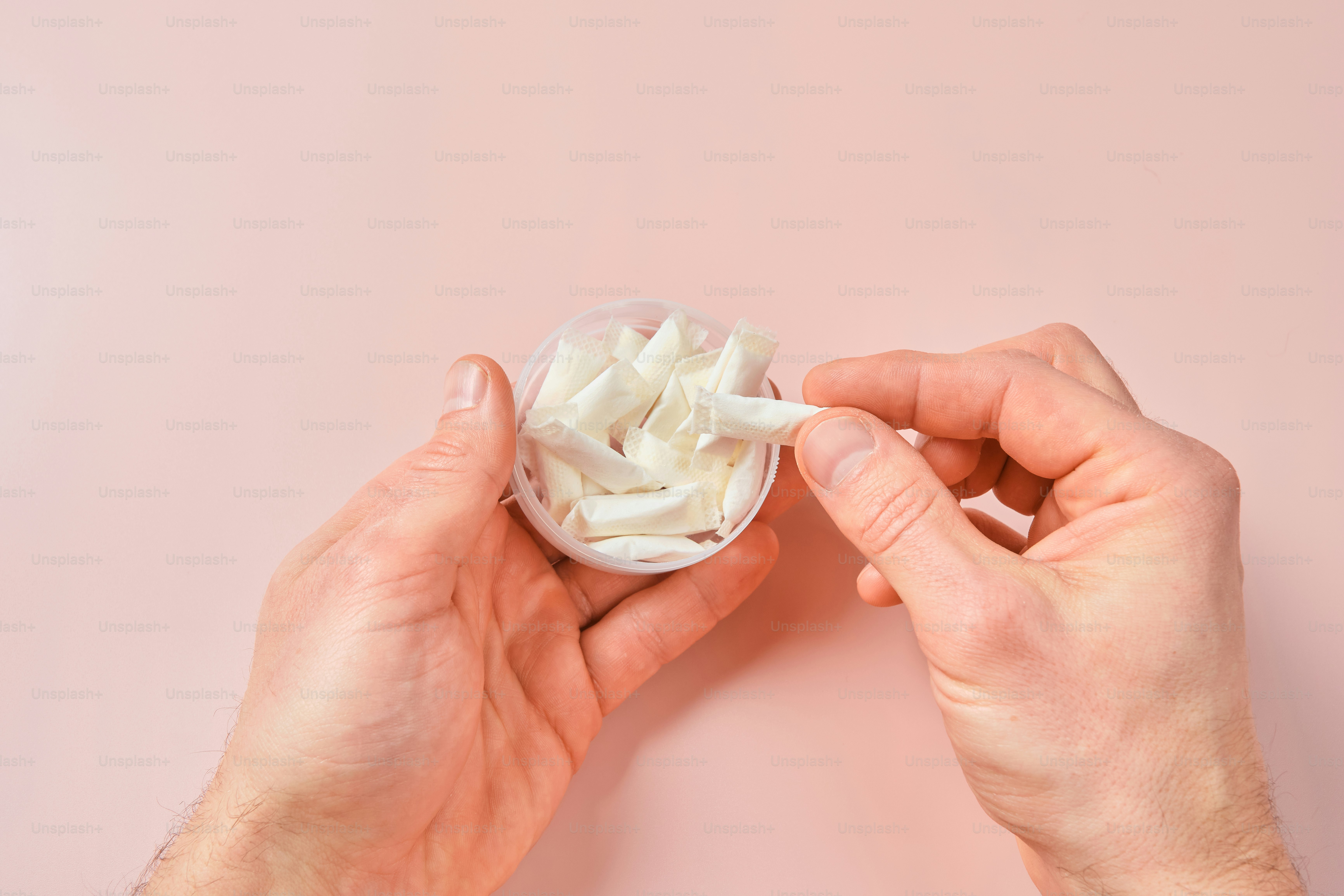 Hände, die einen durchsichtigen Behälter mit weißem Papier halten.