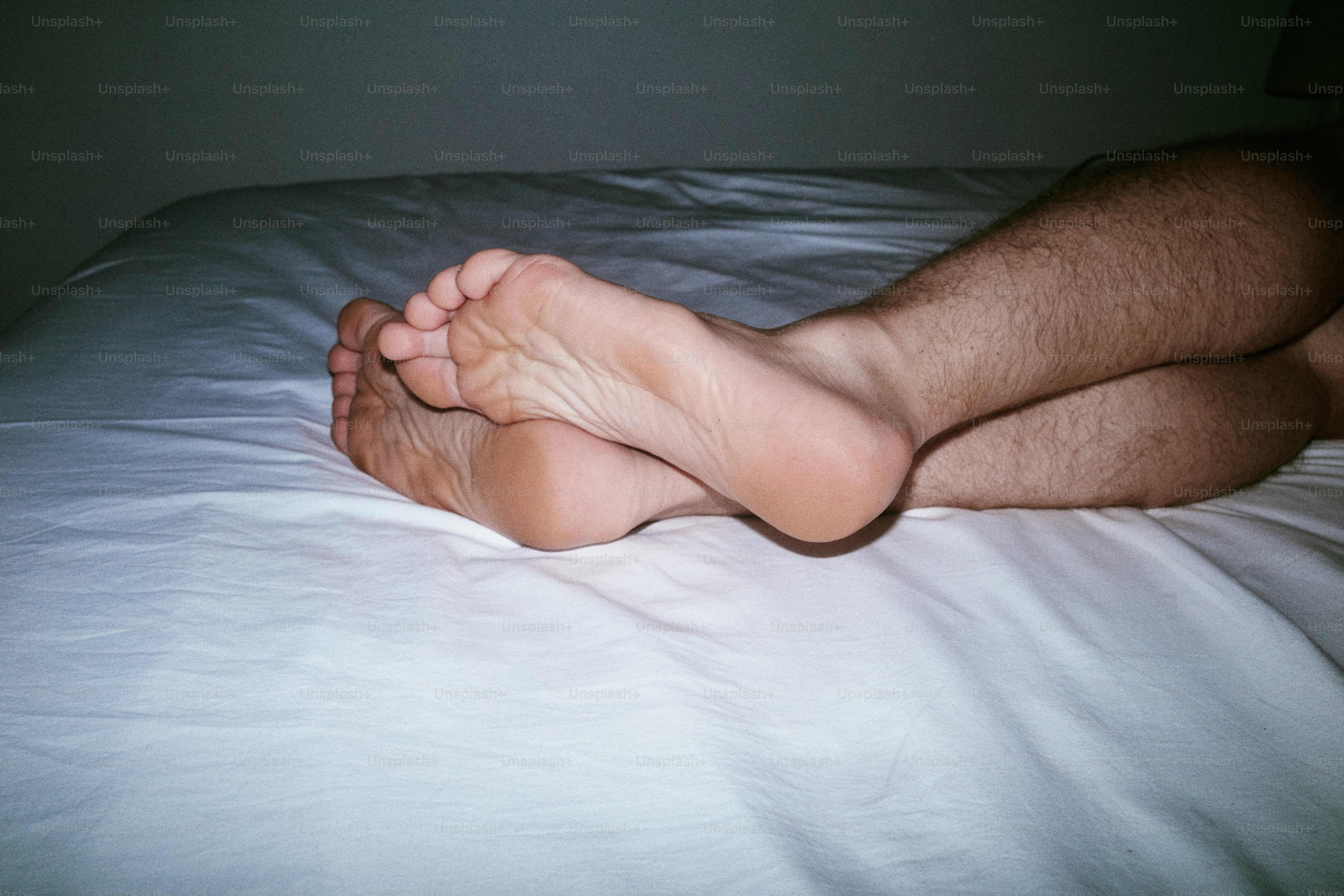 Piedi nudi appoggiati su un letto bianco.