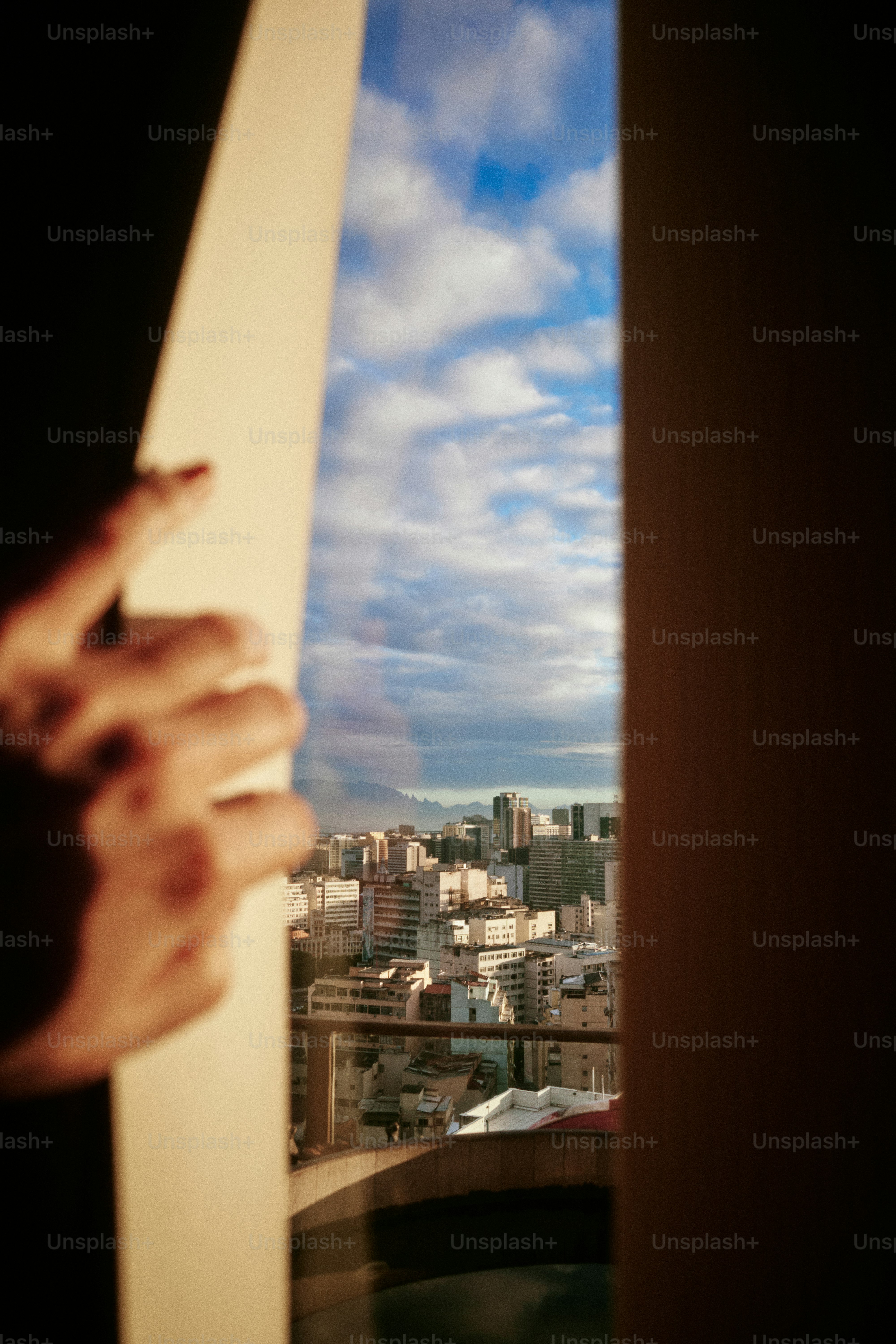 A mão abre uma porta, revelando a vista da cidade.