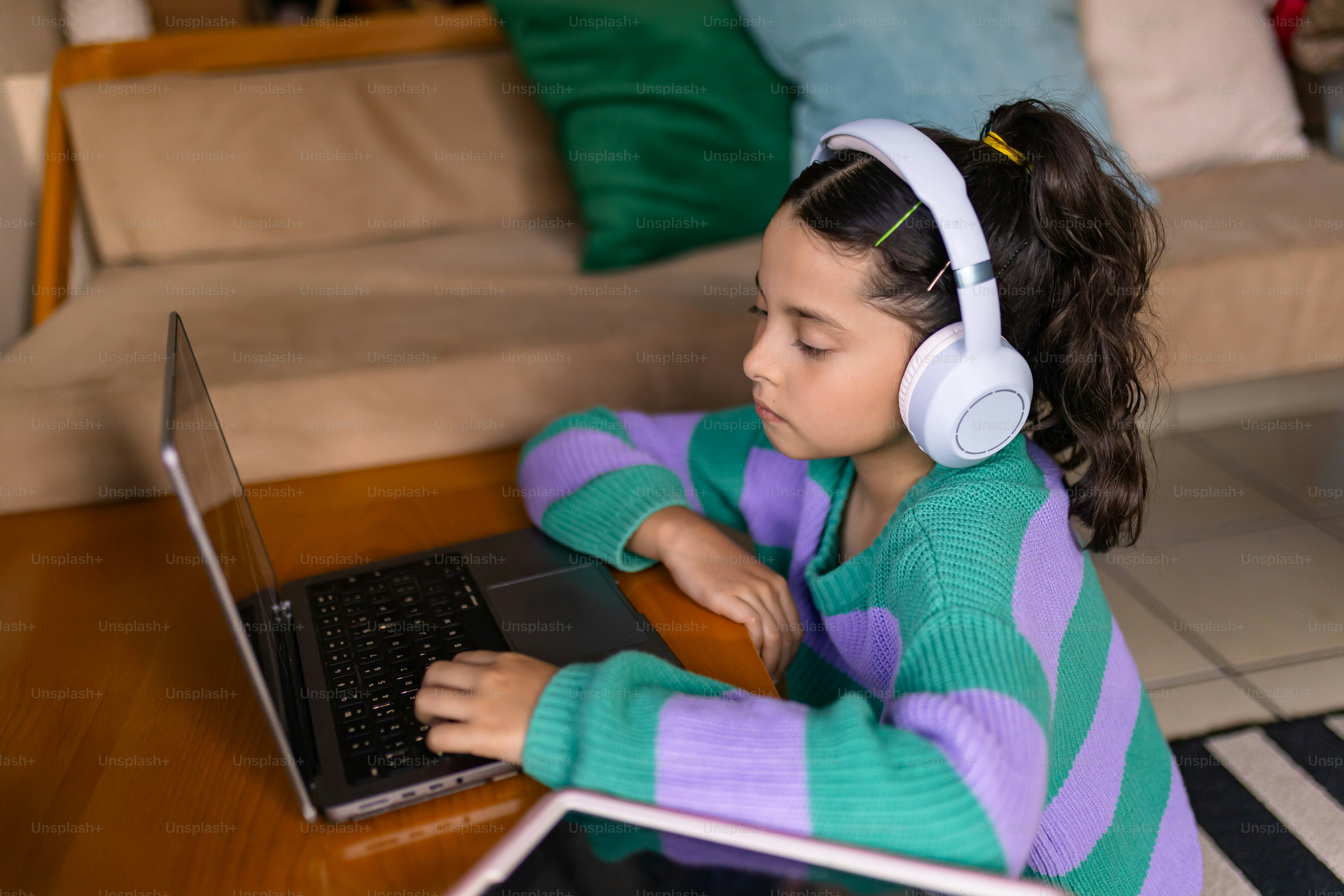 Girl studies on laptop with headphones on.