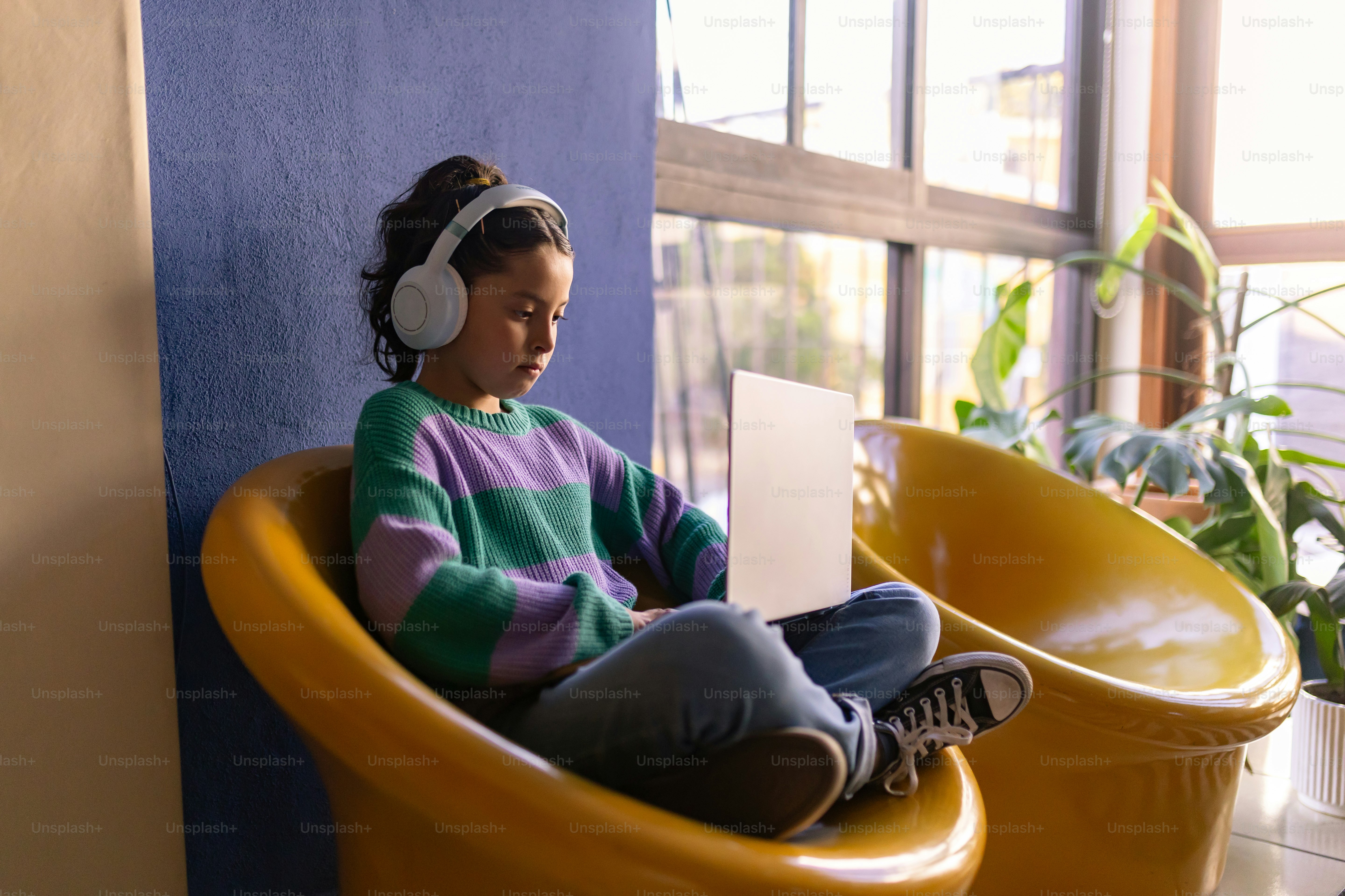Girl listens to music while using a laptop.