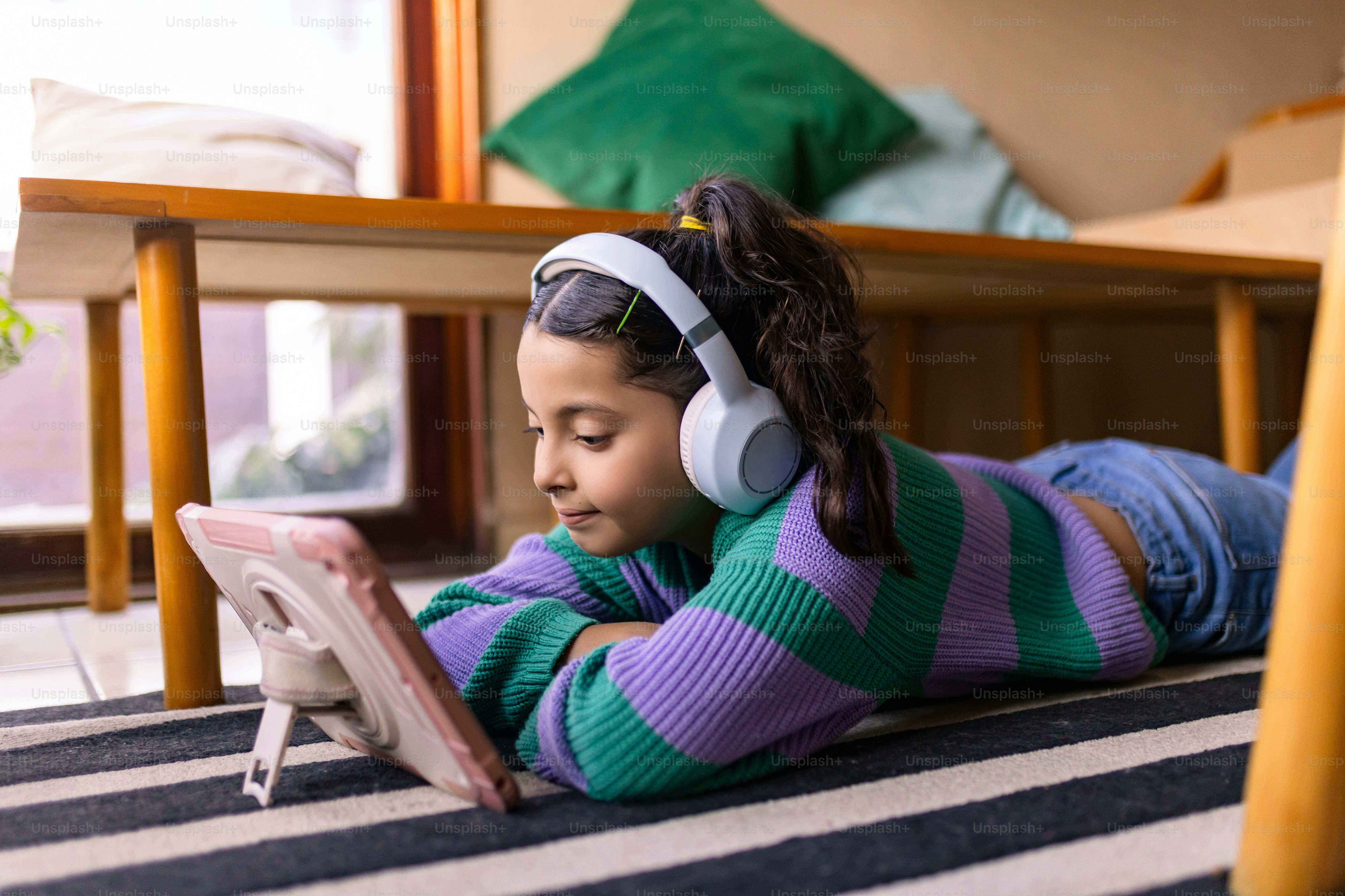 Girl uses a tablet while wearing headphones.