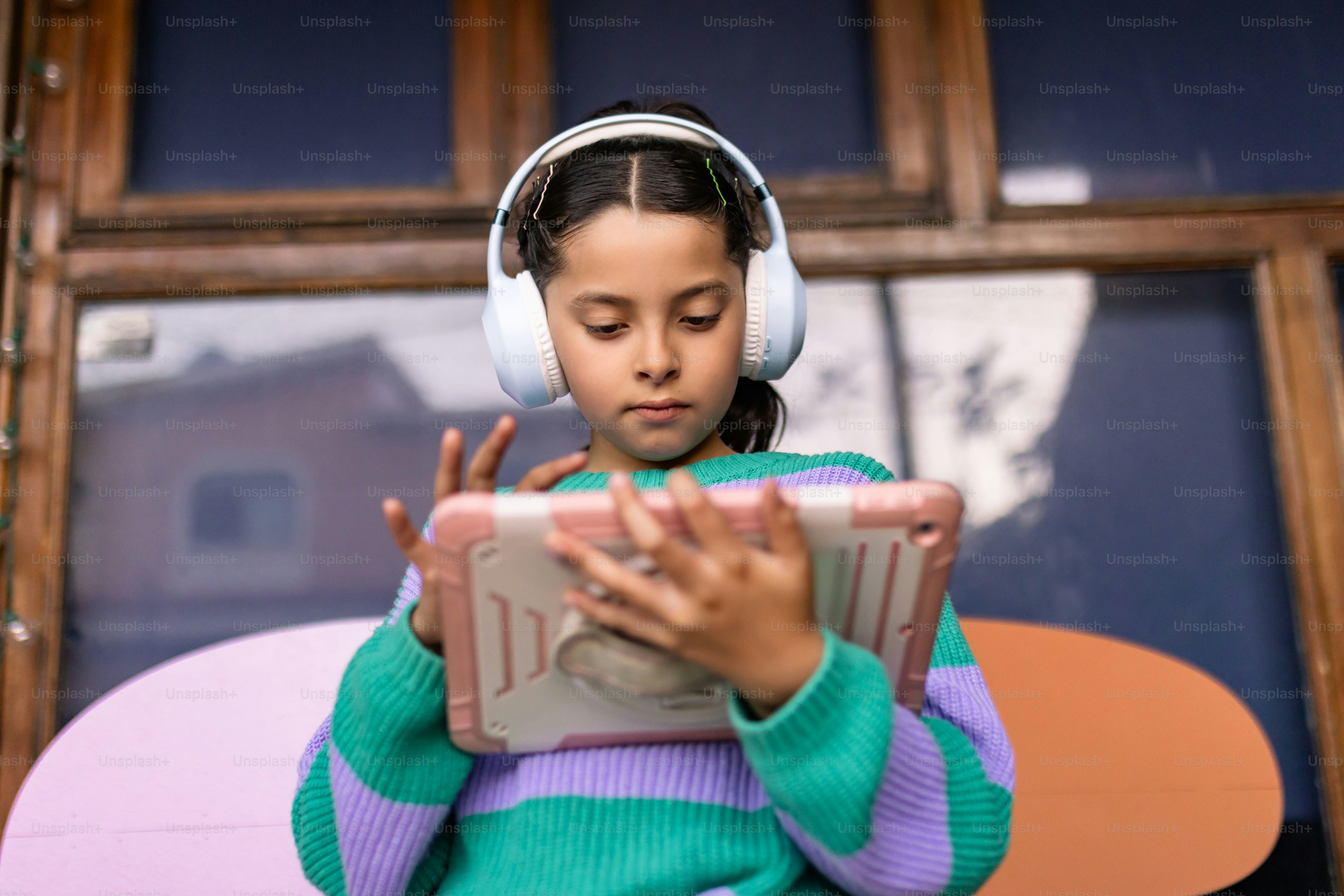 Girl wearing headphones and using a tablet.