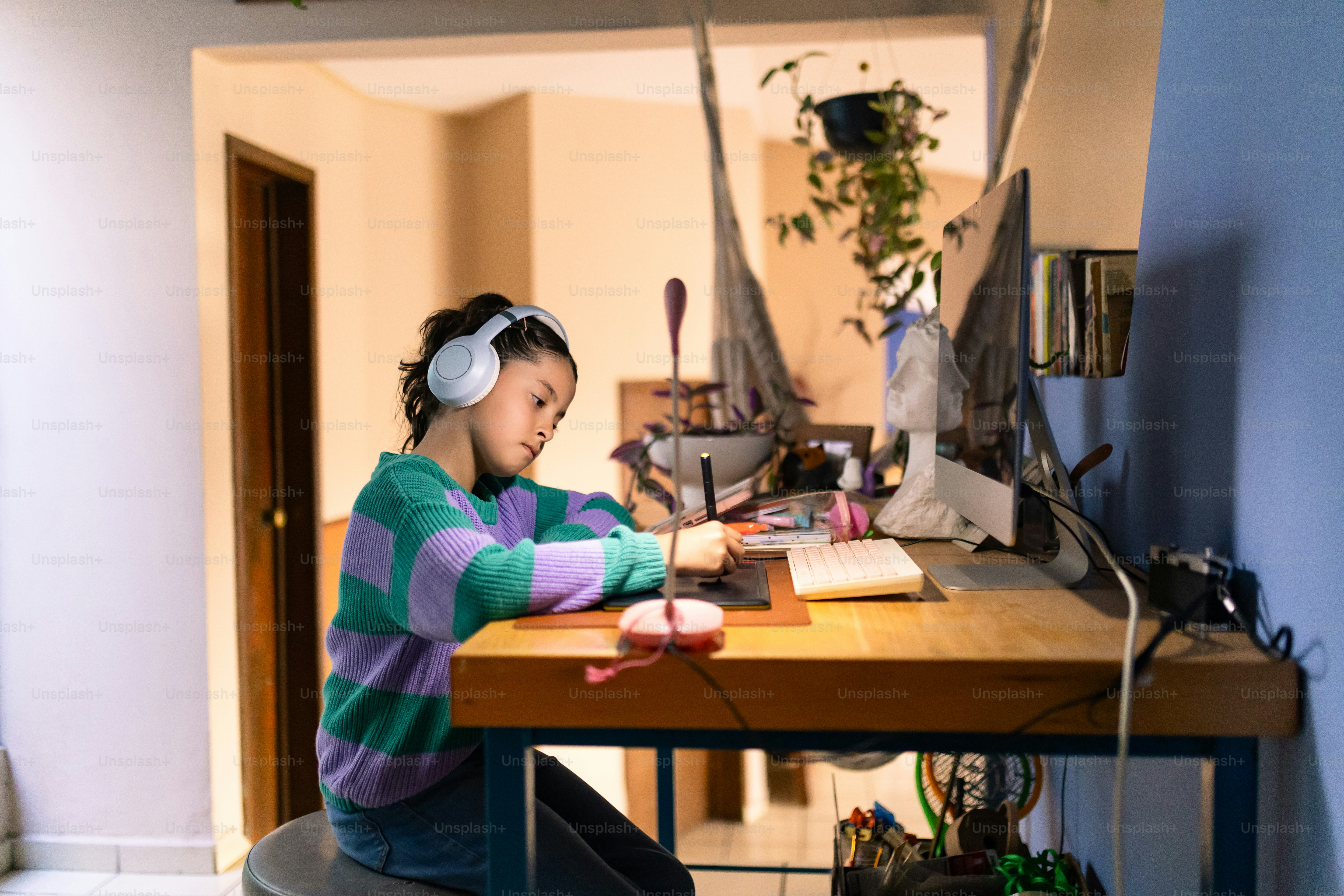 A girl works on her computer with headphones.