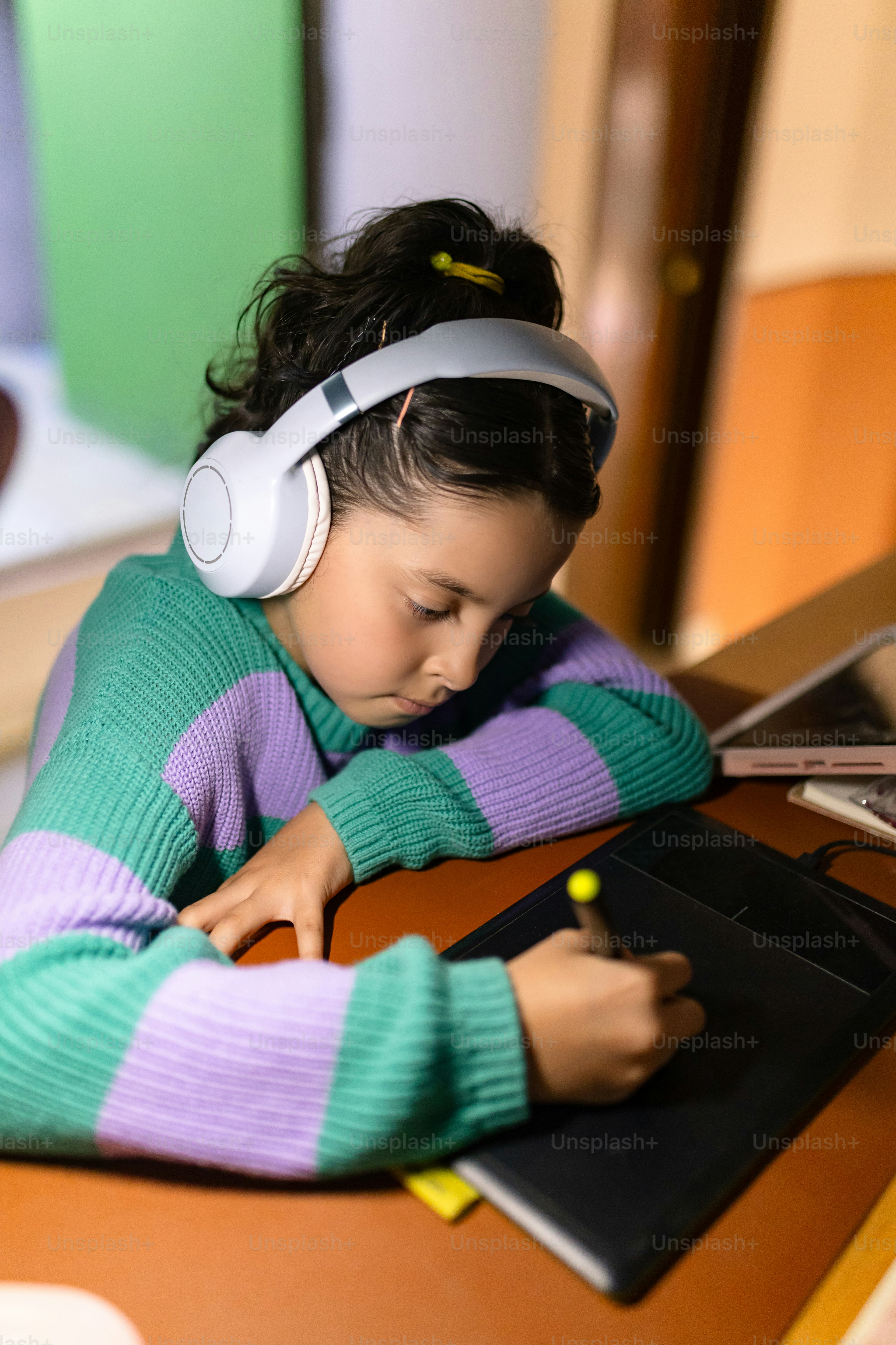 Girl with headphones draws on a tablet.