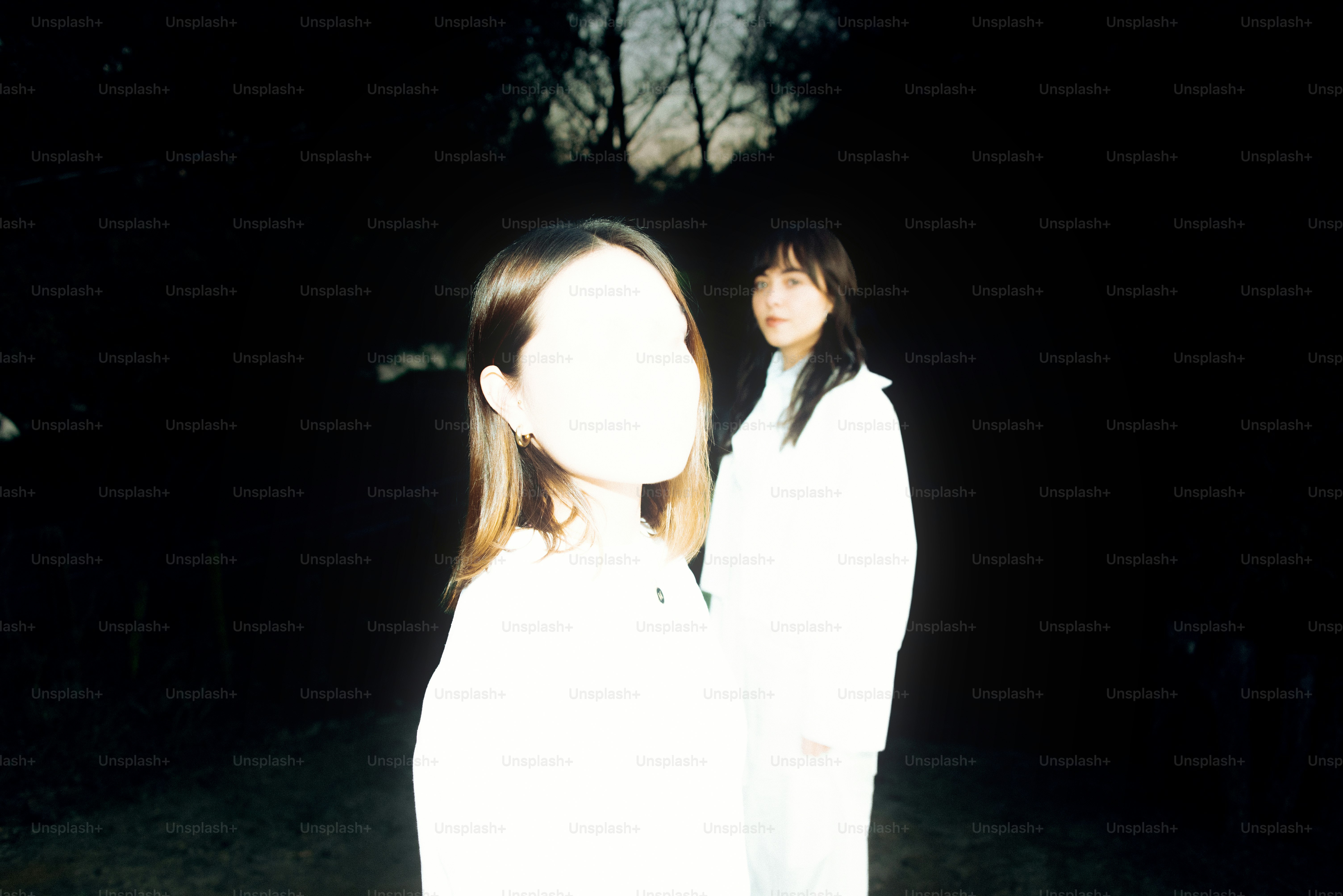 Due donne in bianco si trovano in una foresta oscura.