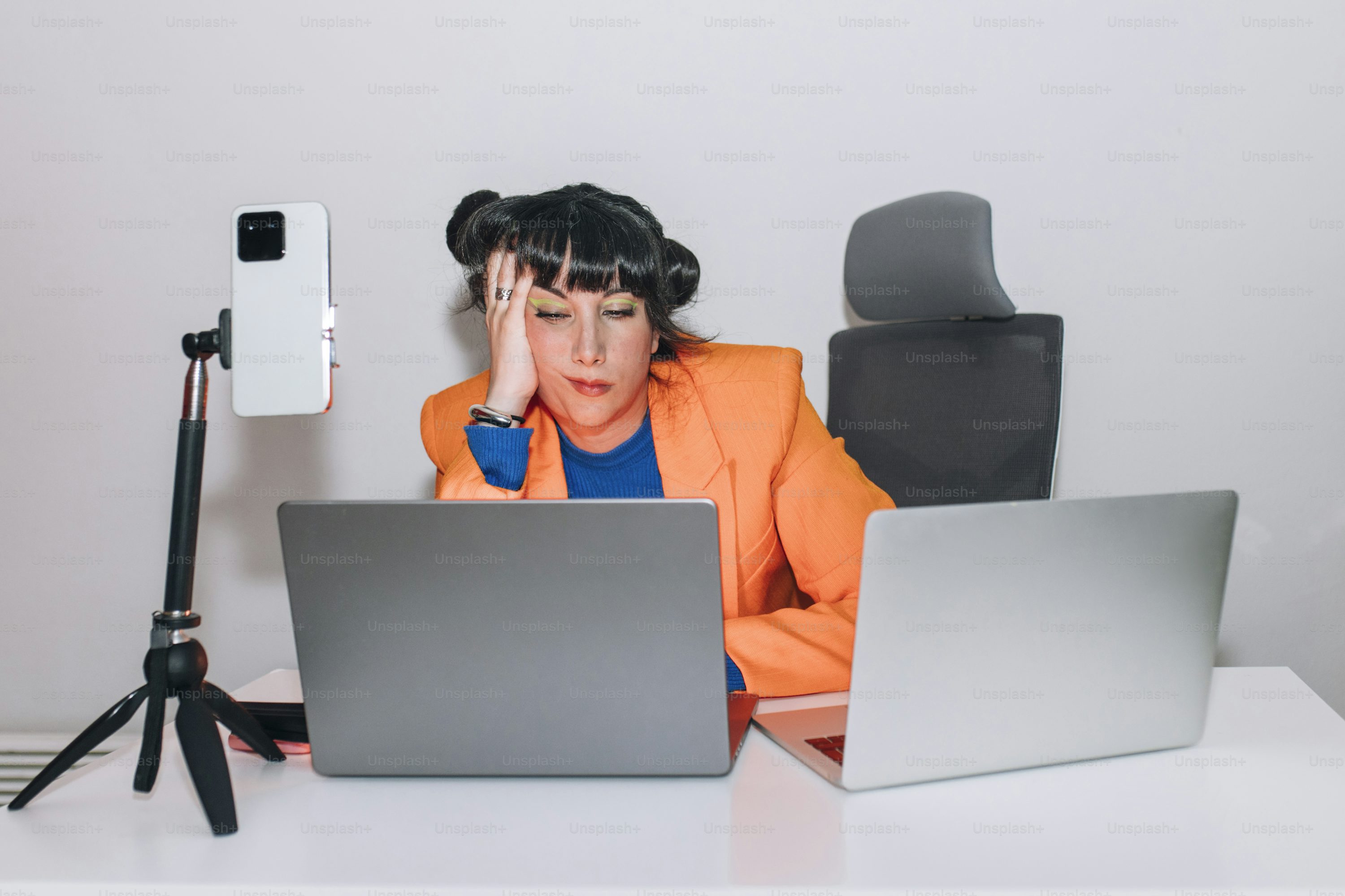 Exhausted woman works on multiple screens.