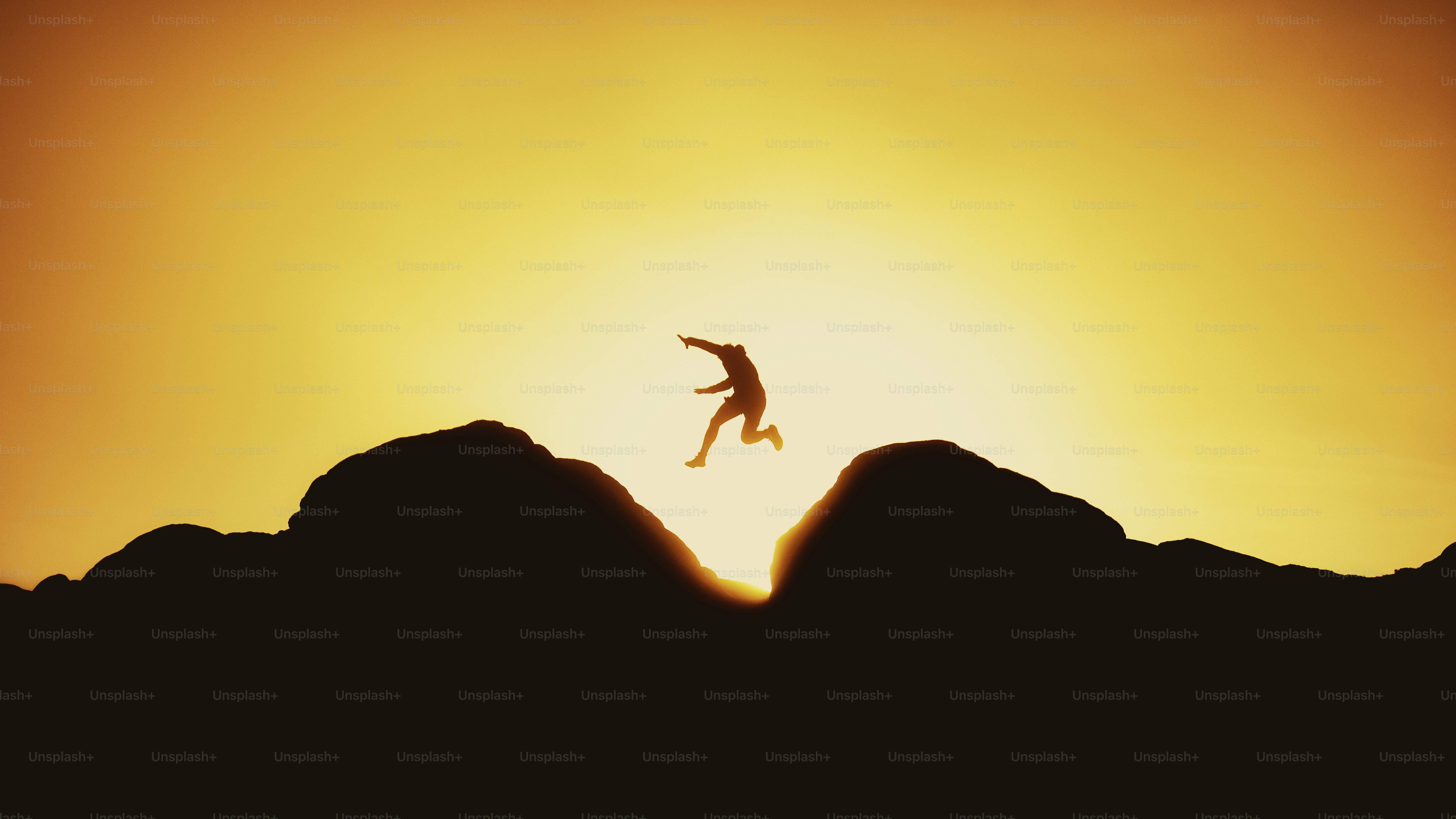 Person leaps over a mountain gap at sunset.