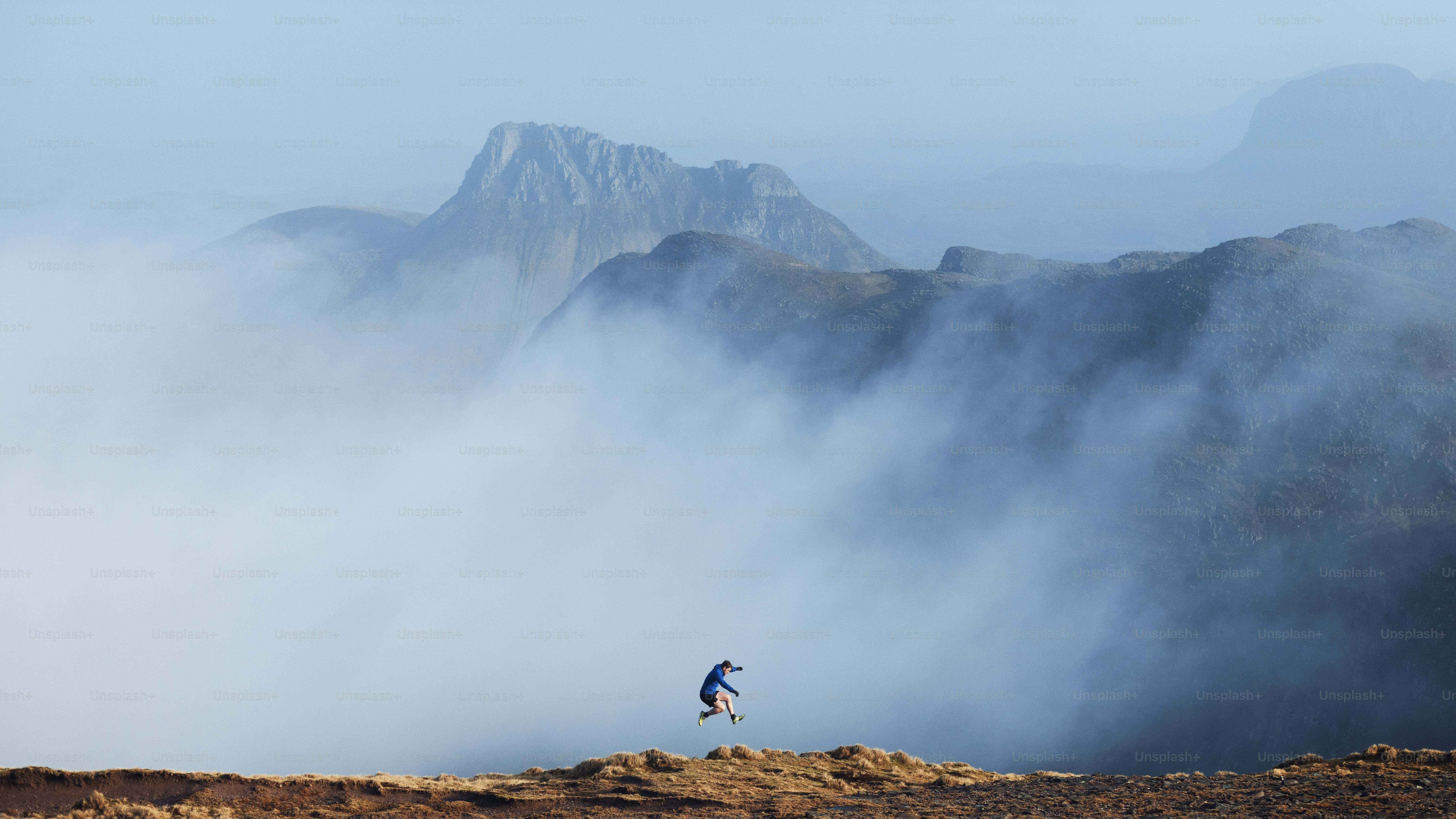 A person jumps in misty mountains.