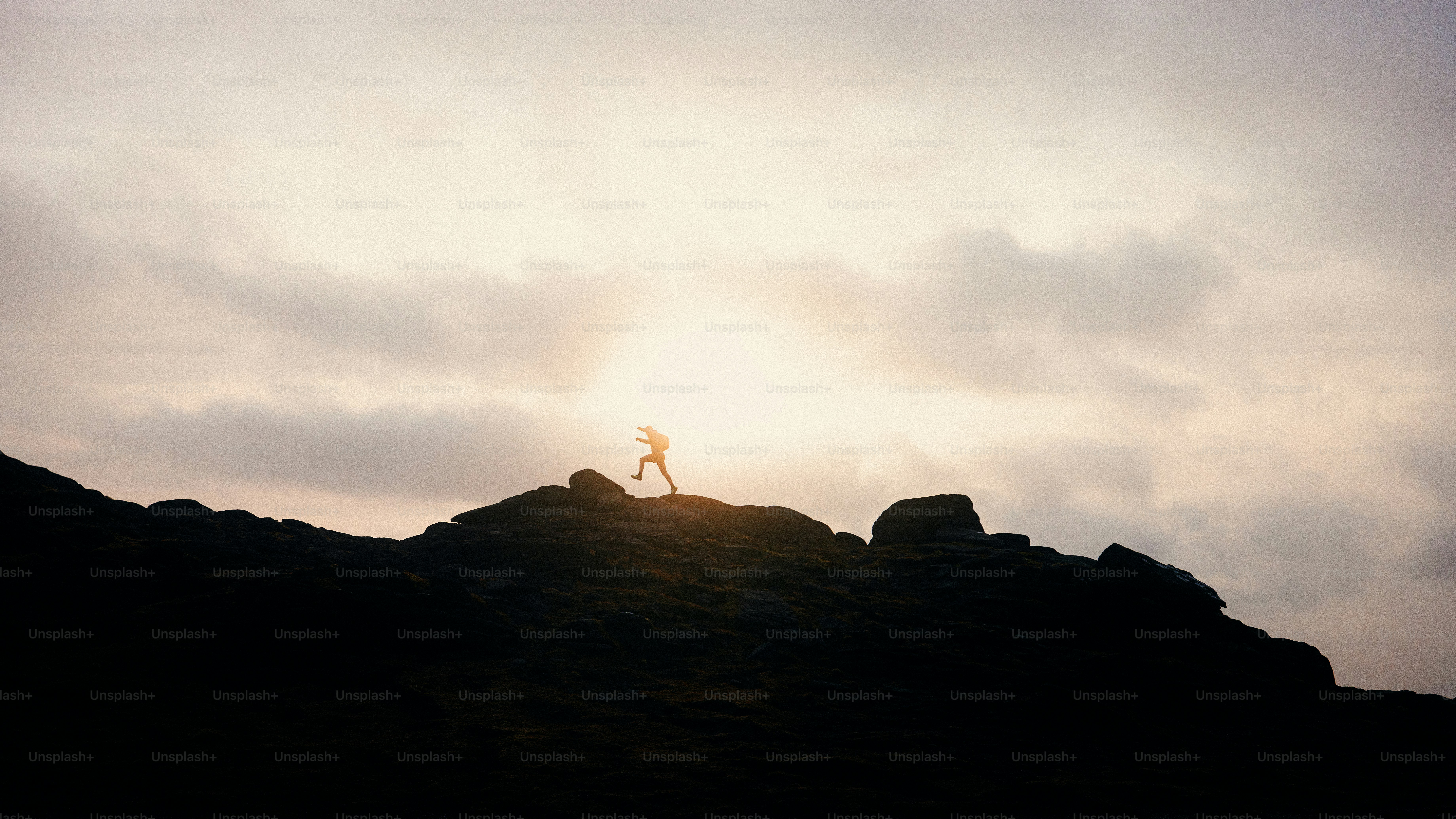A person silhouetted on a mountain at sunset.