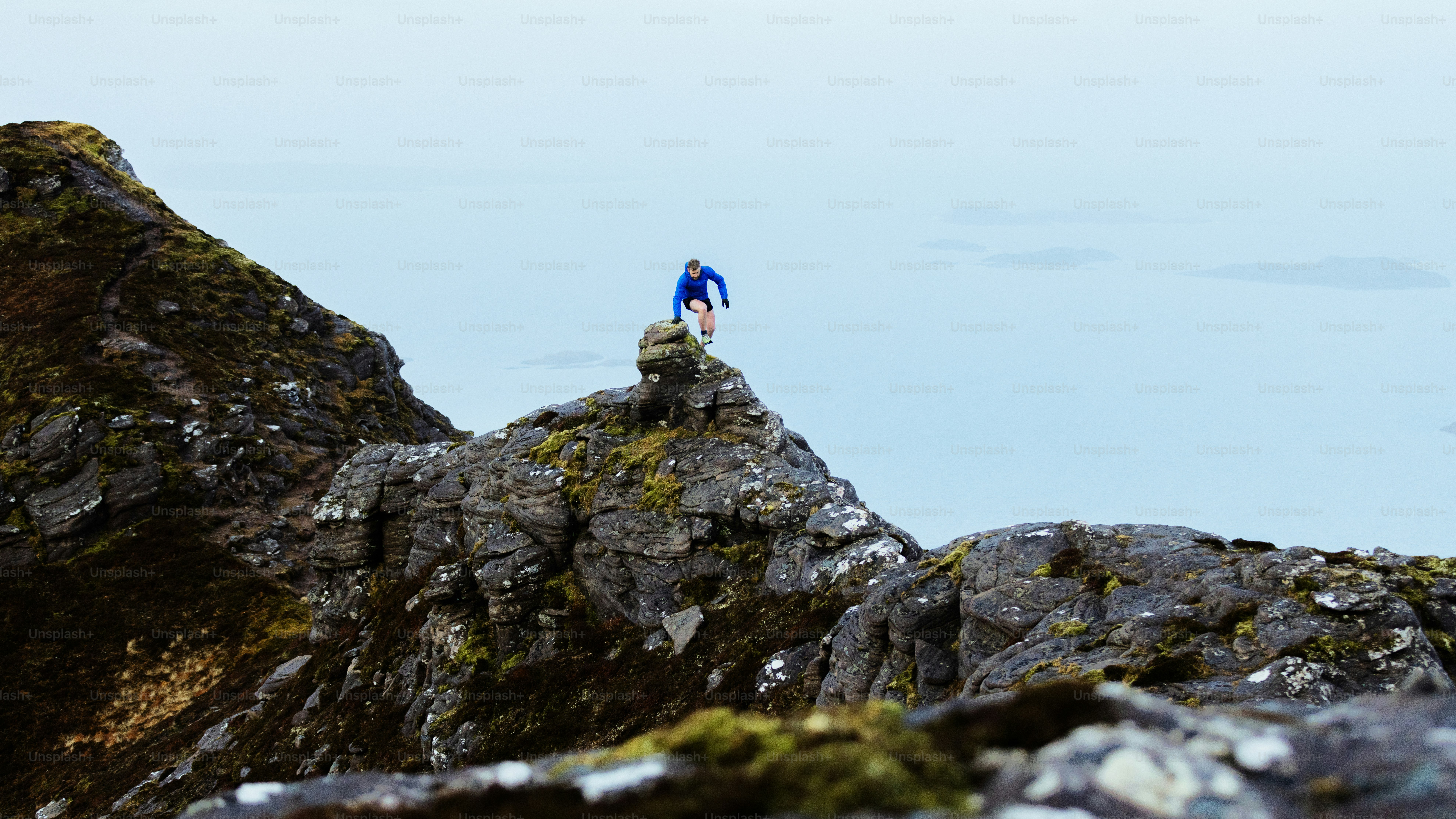 A person stands atop a rocky mountain.