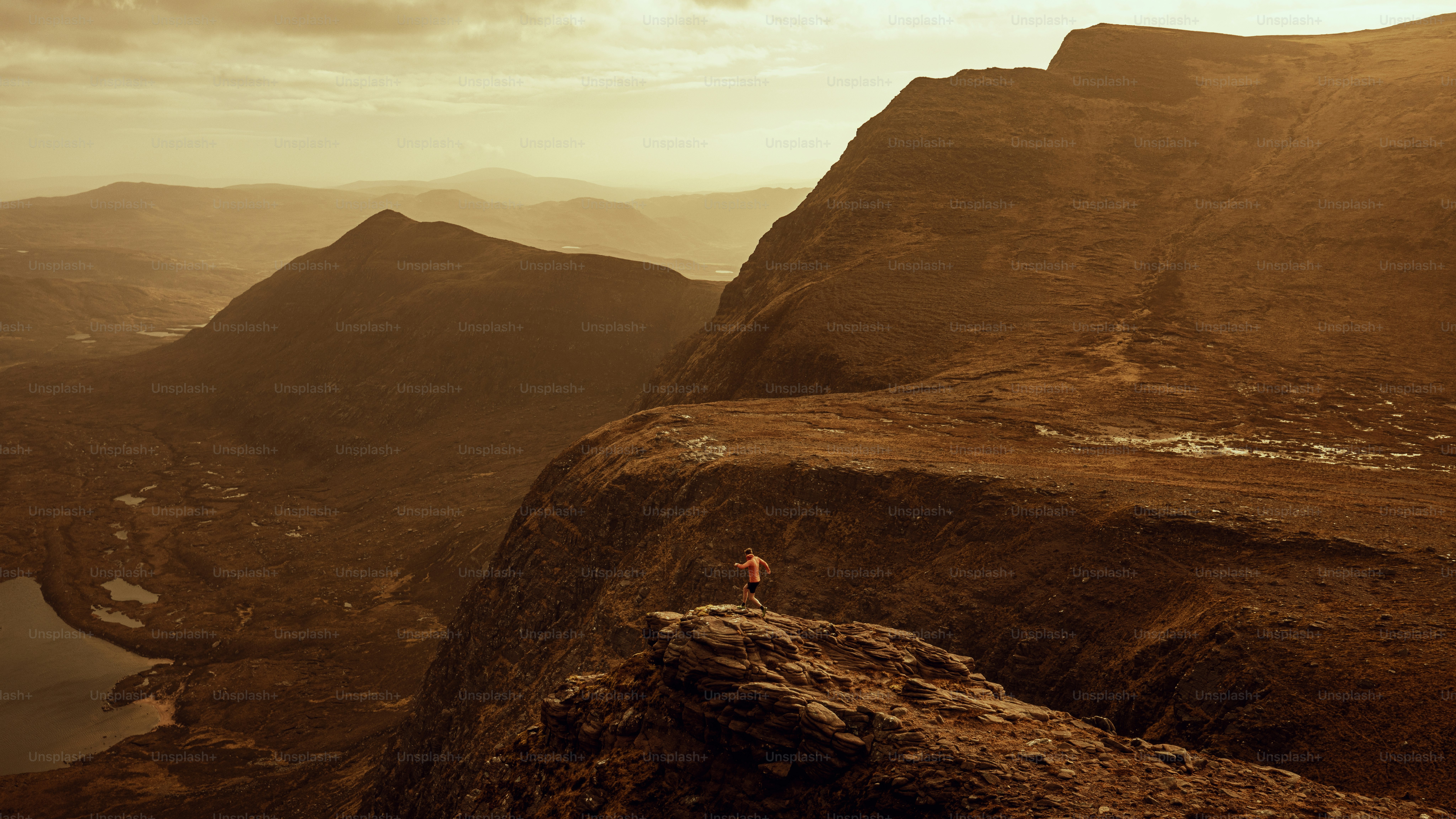 Person stands atop a mountain, overlooking the landscape. photo ...