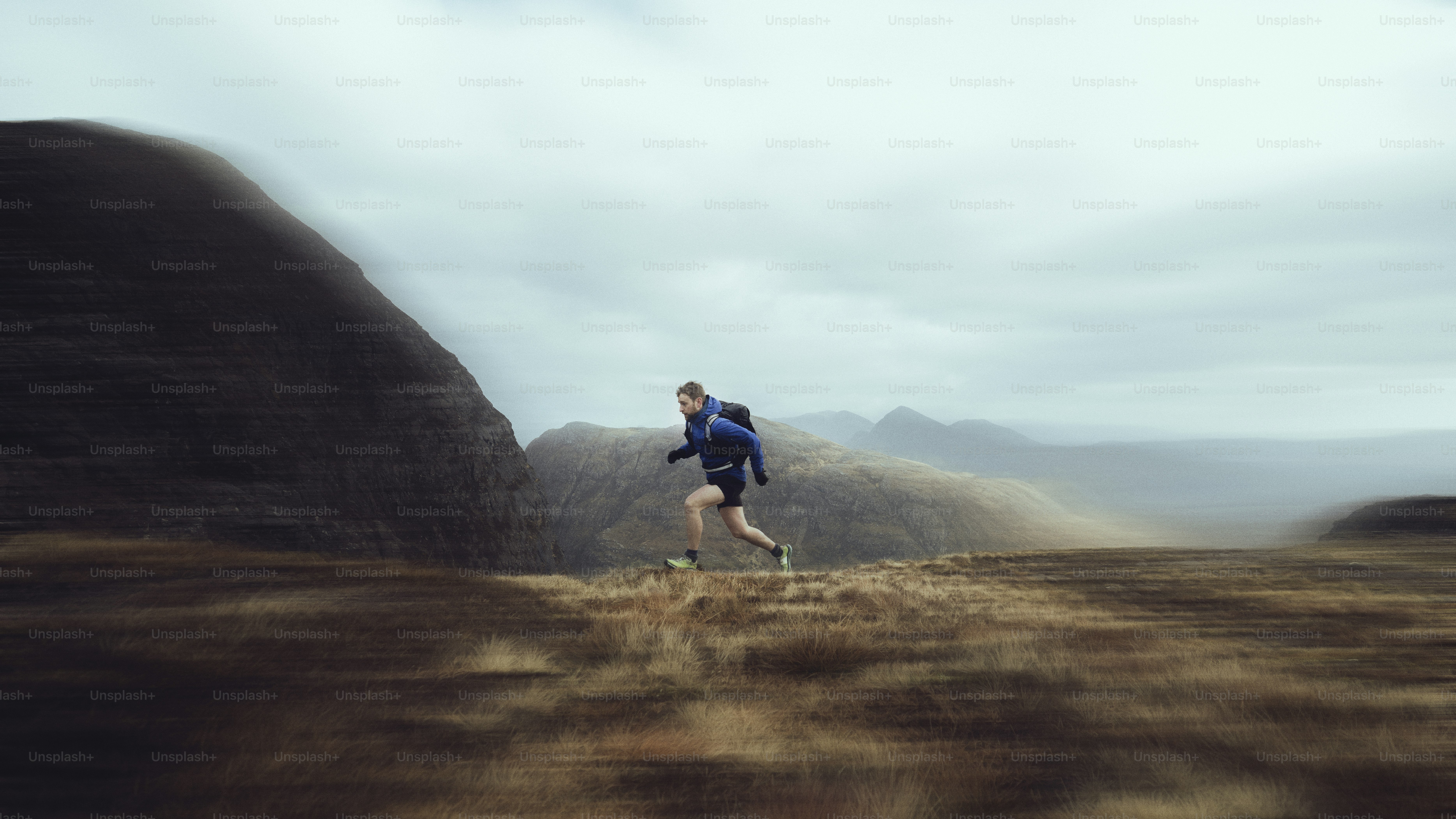 Runner sprints across a field with mountains in background.