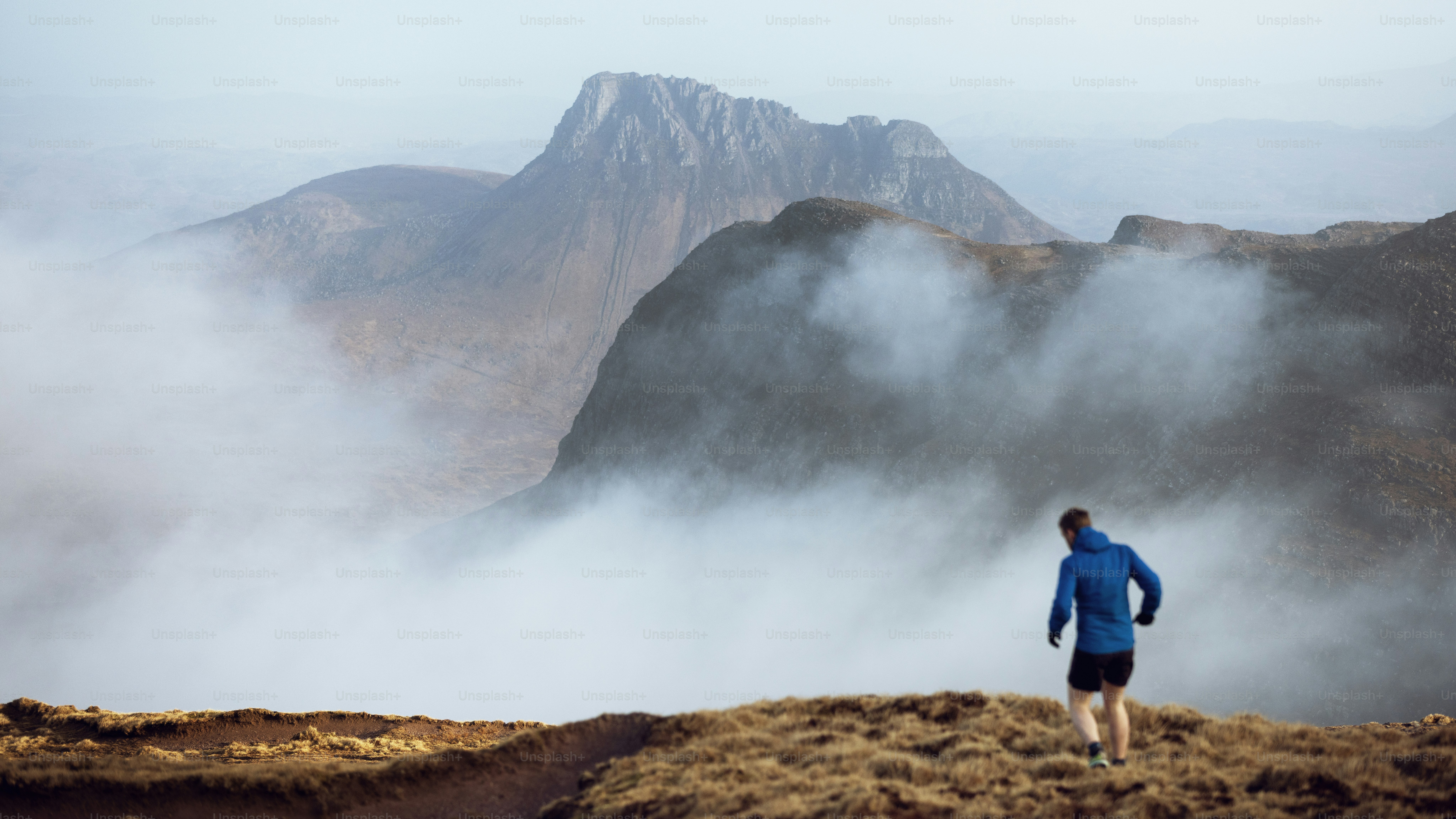 Runner traverses a foggy mountain trail.