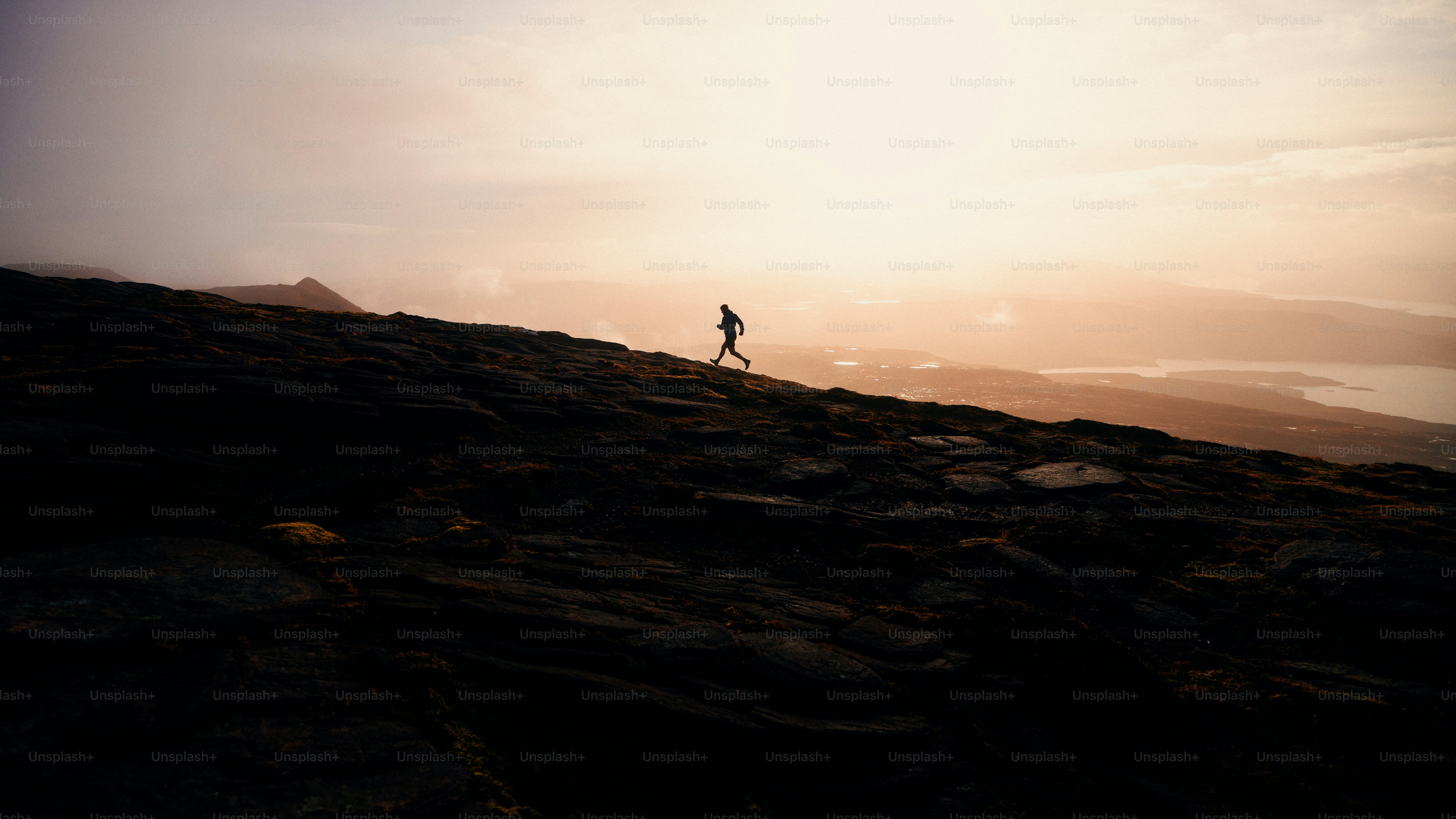 Runner ascends a mountain at sunset.