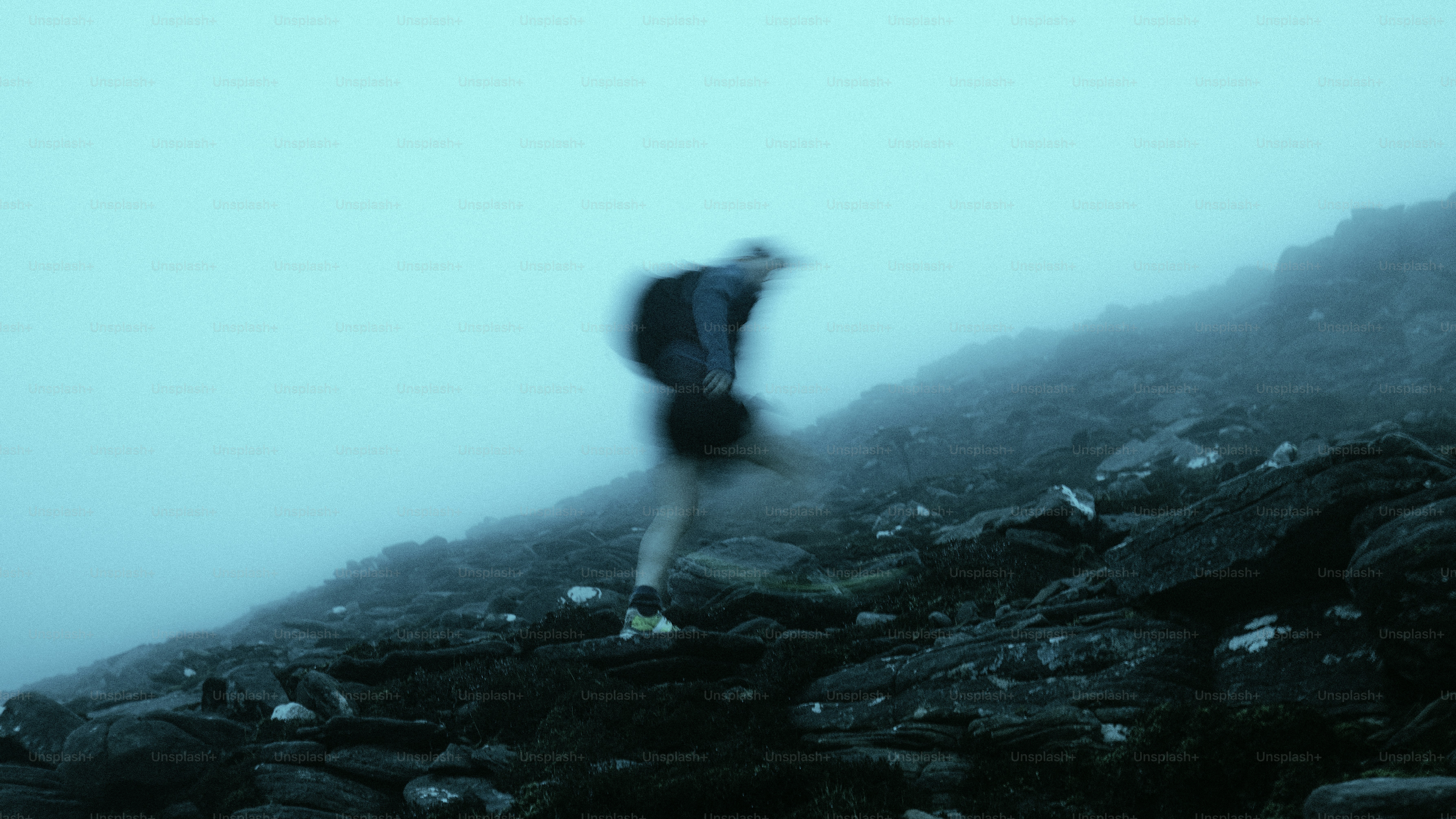 Der Wanderer steigt einen felsigen, nebligen Bergpfad hinauf.