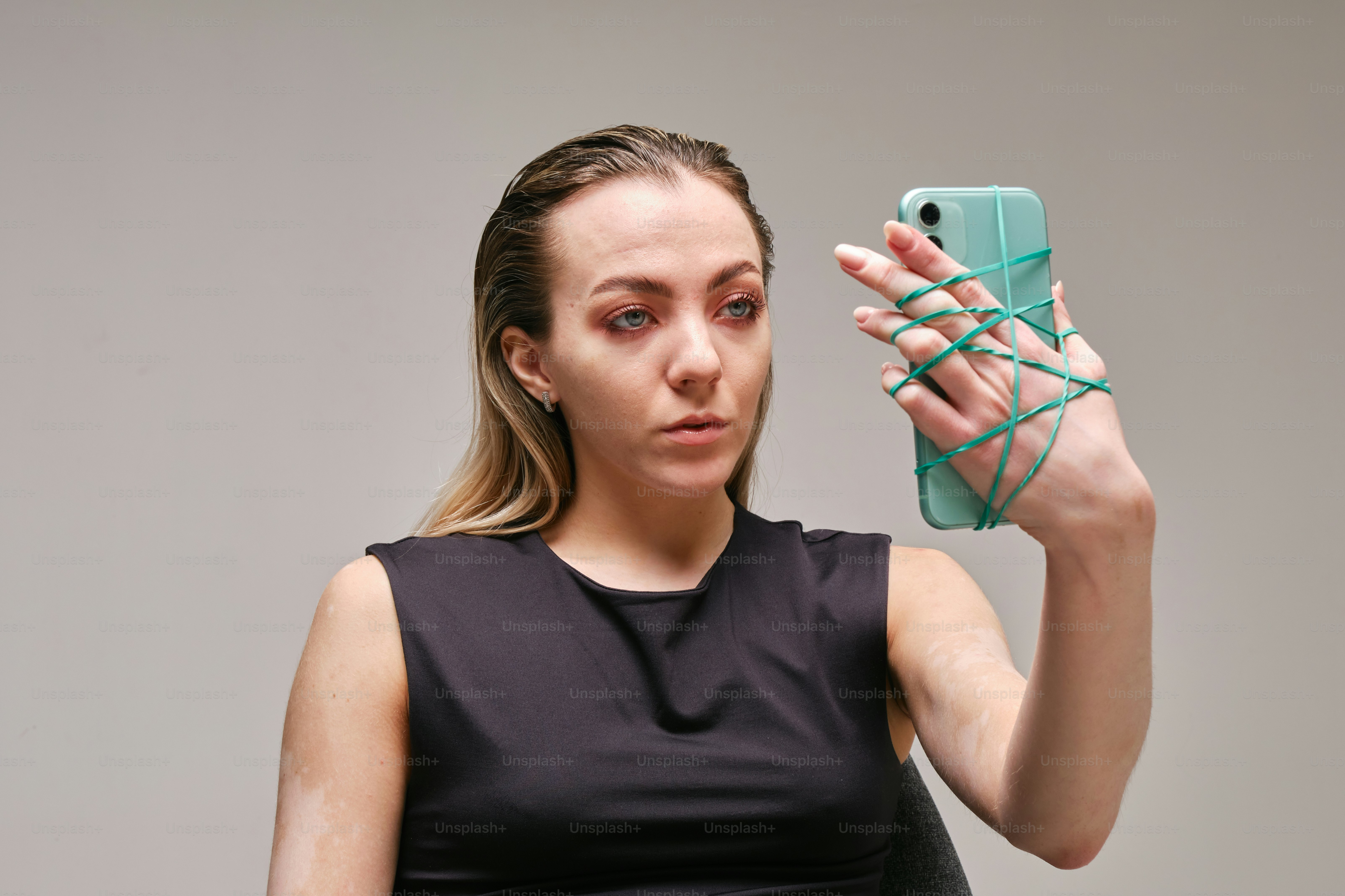 Woman holds phone with rubber bands around her hand.