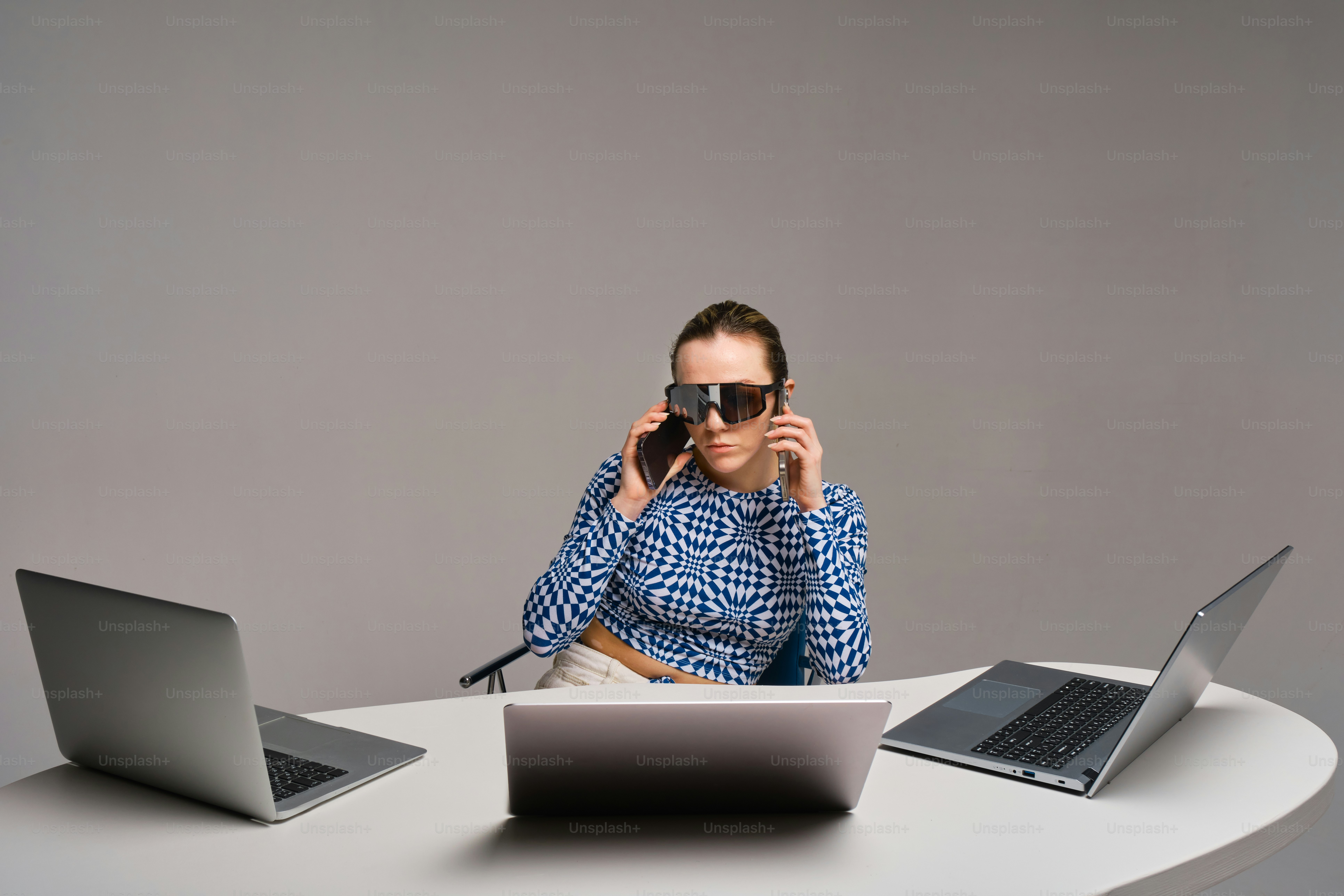 Woman with three laptops talks on the phone.
