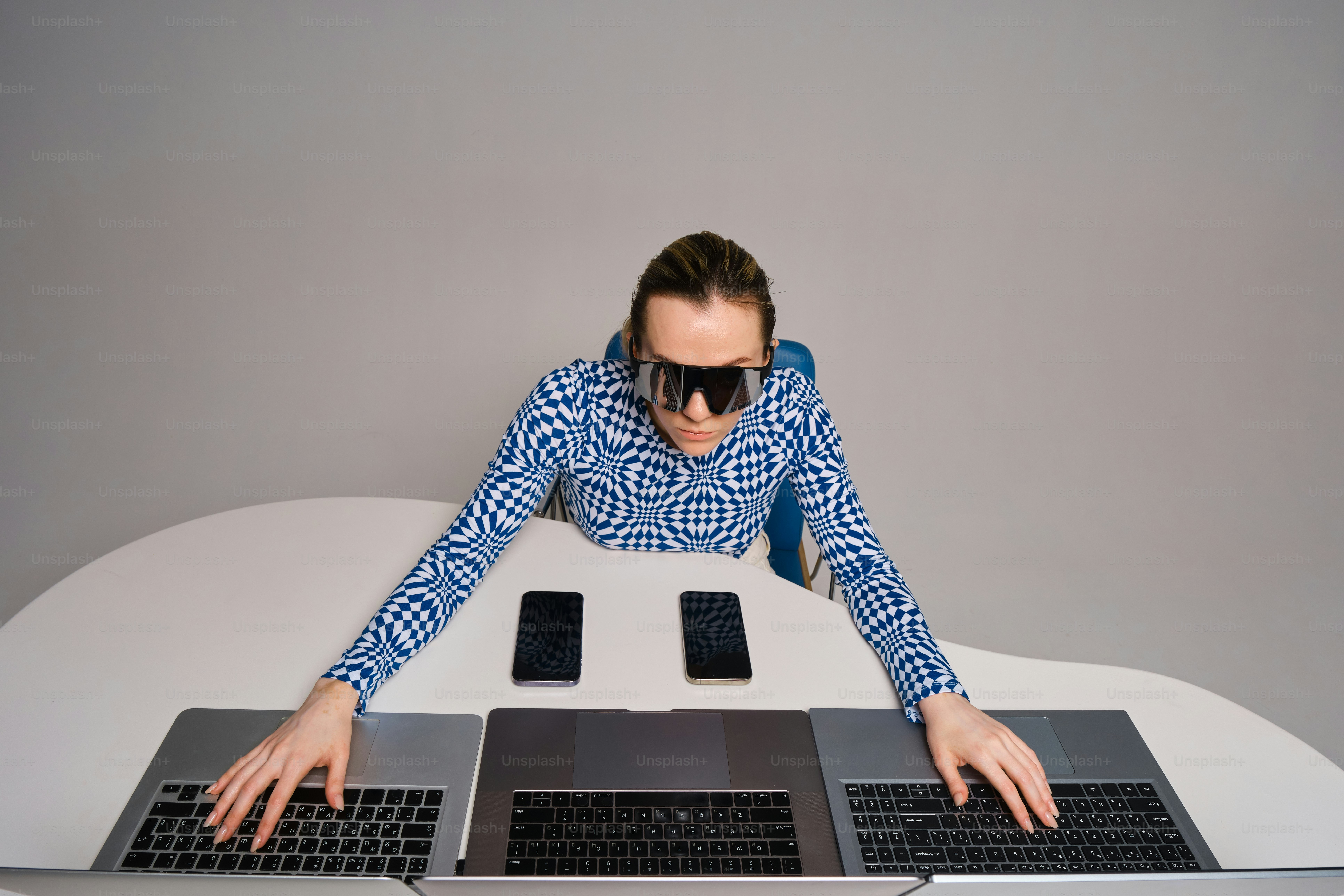 Person working with multiple laptops and phones.