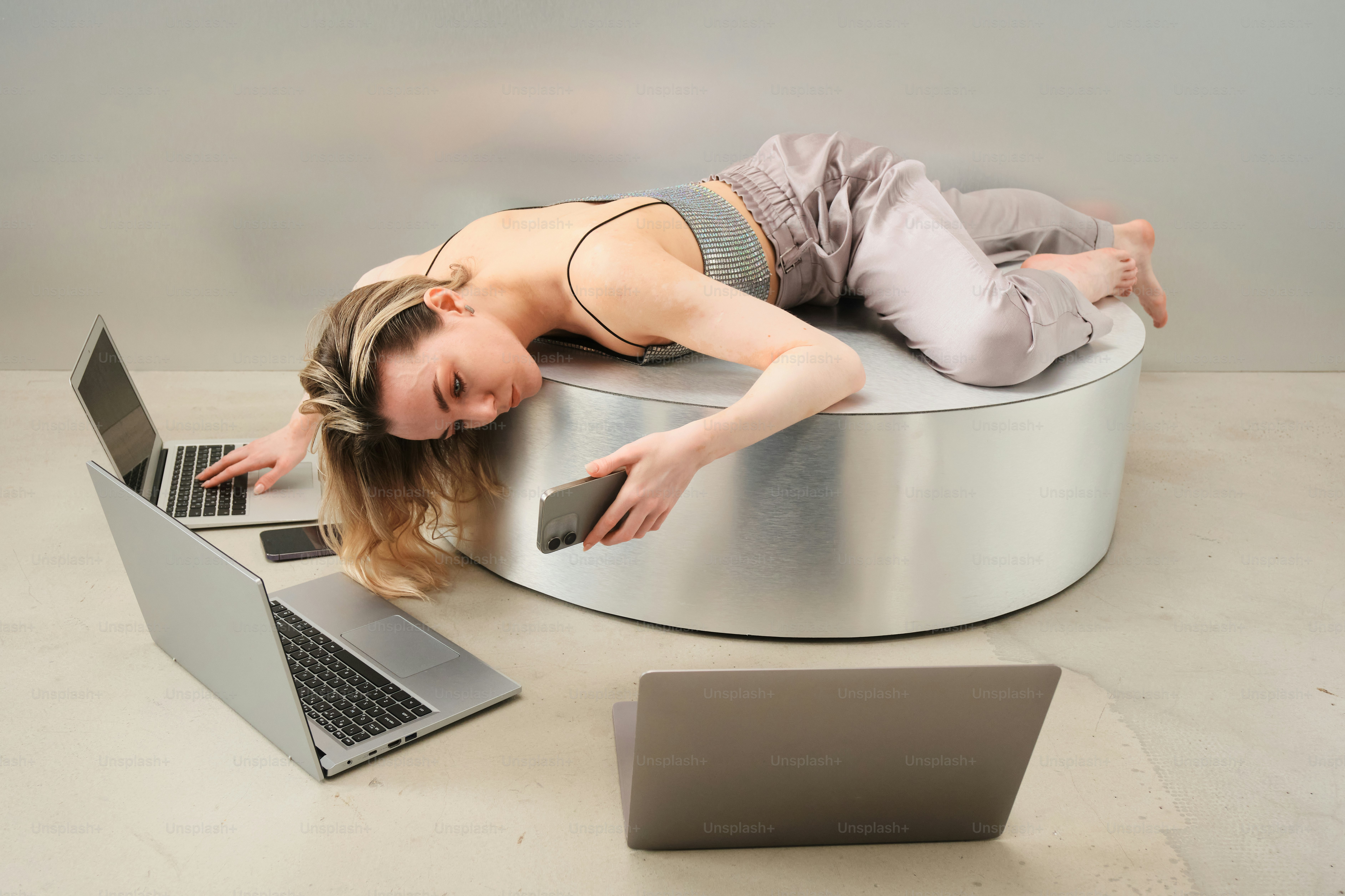 Exhausted person lies on table surrounded by electronics.