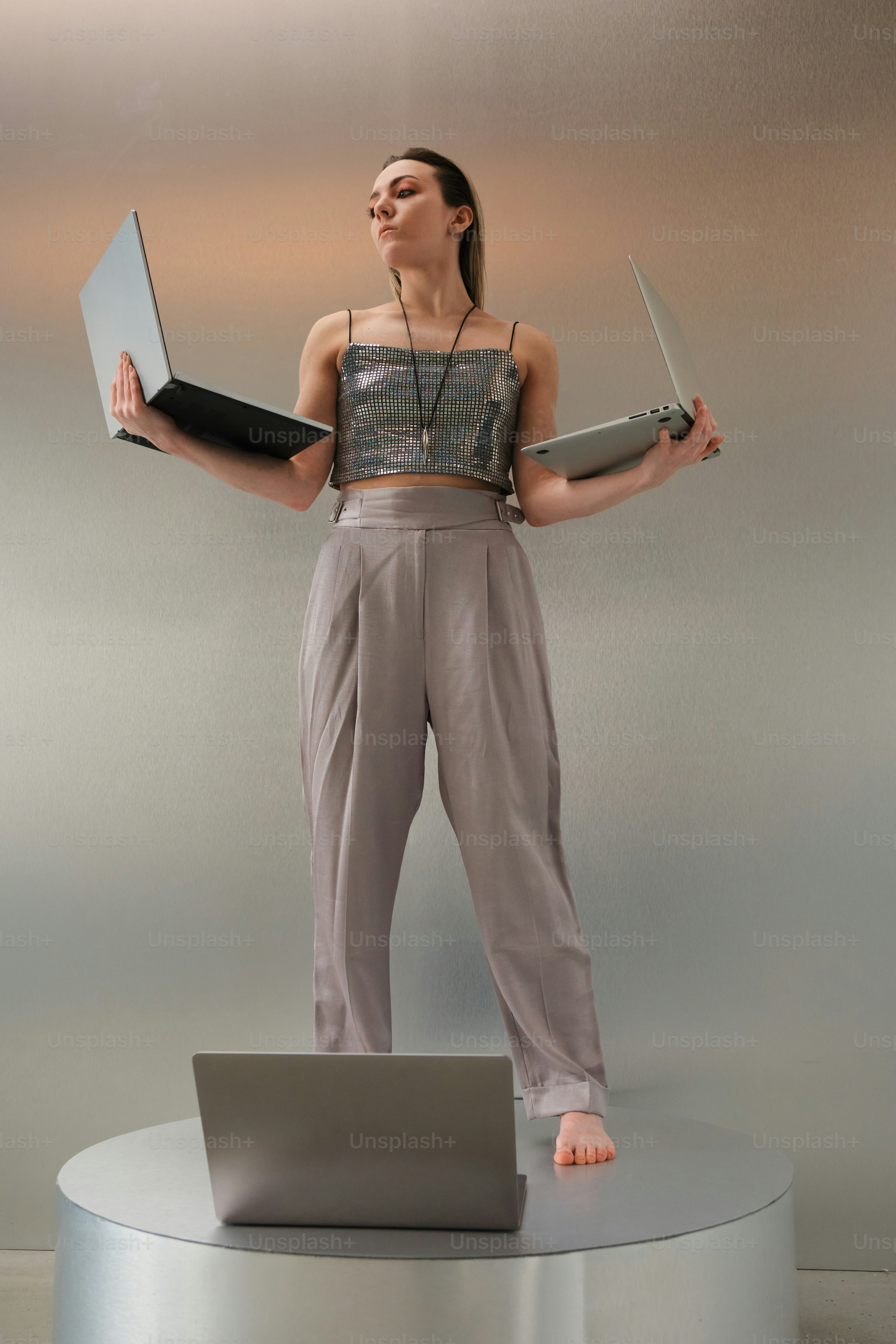 Woman juggles laptops, embodying multitasking.