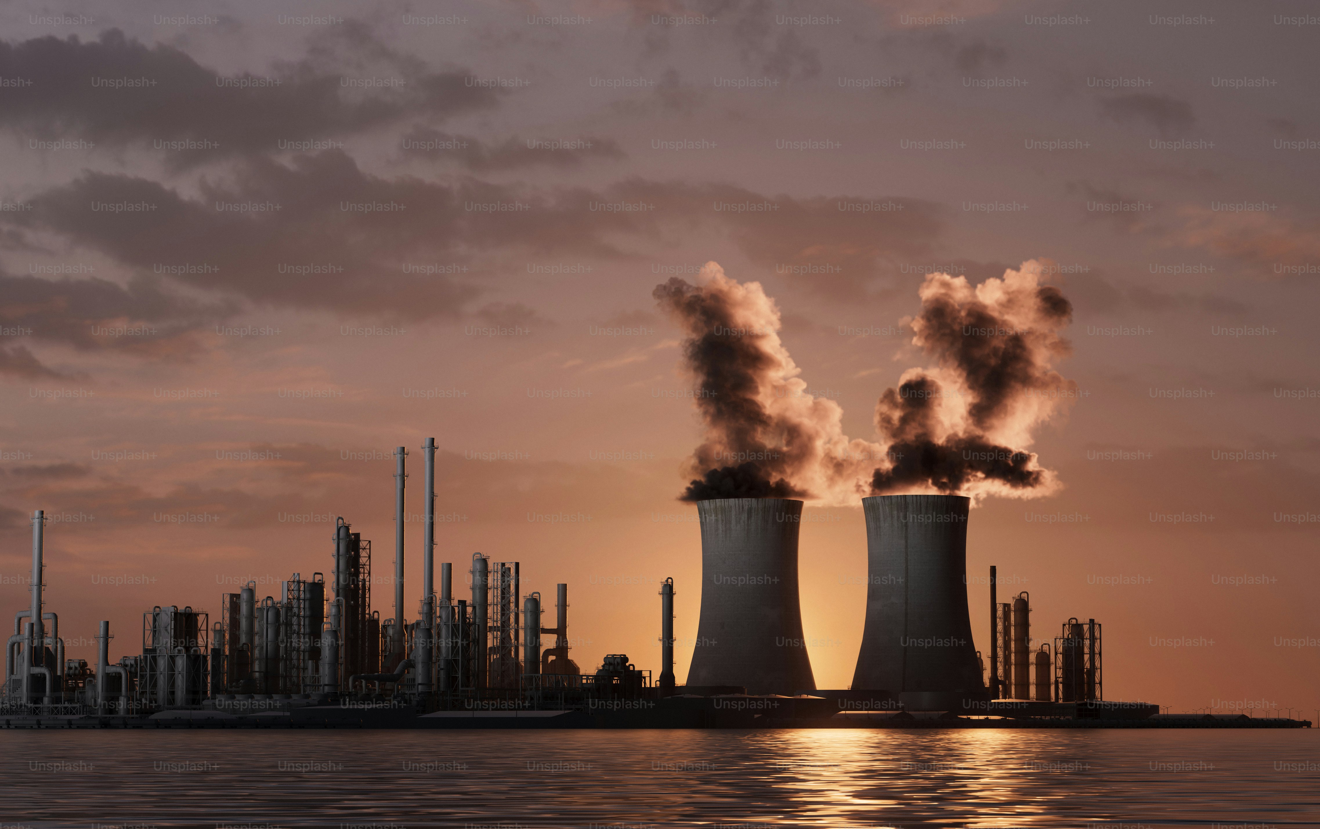 Power plant steaming at dusk near the water.