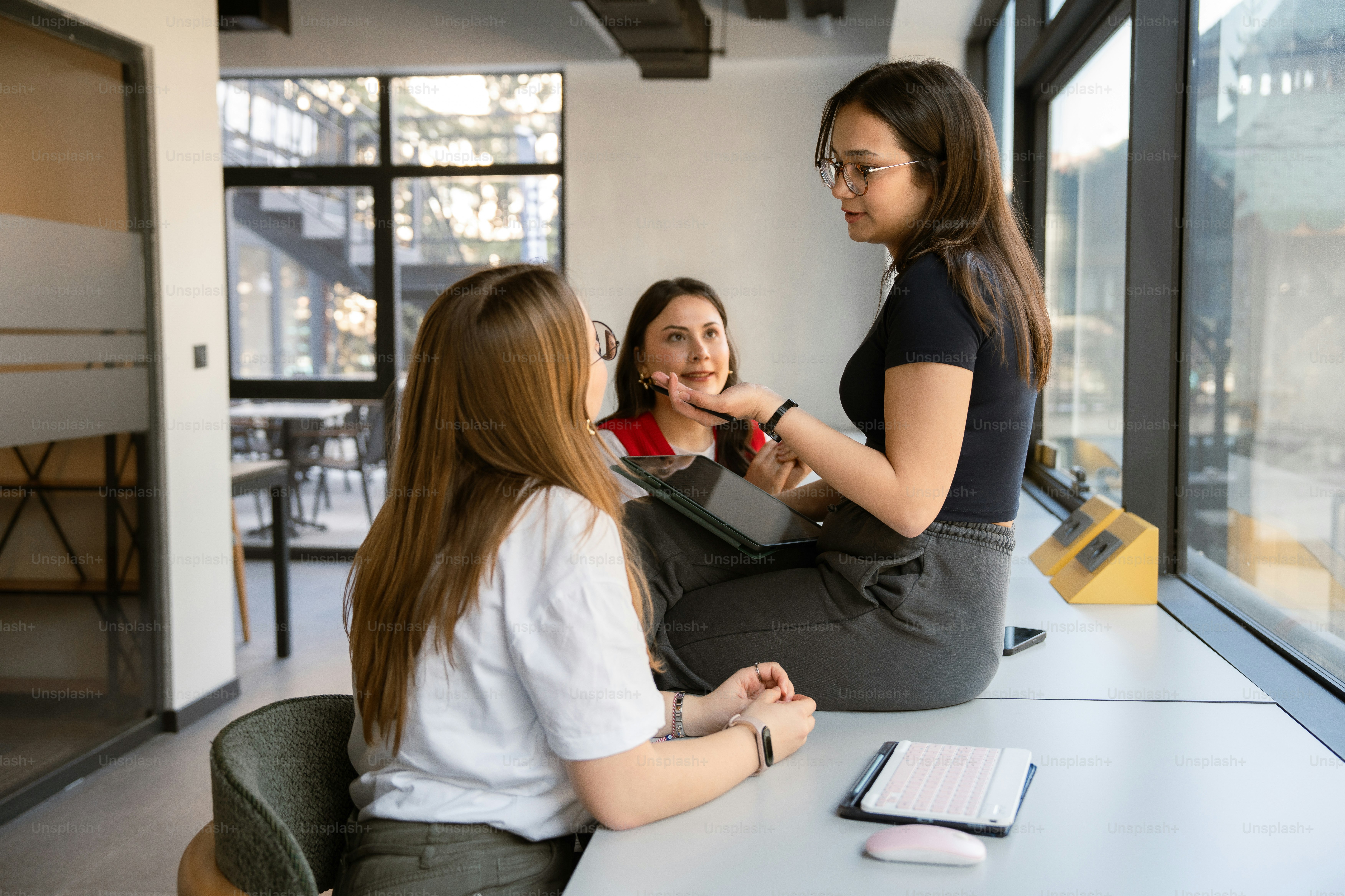 Three women collaborate in a bright office setting.